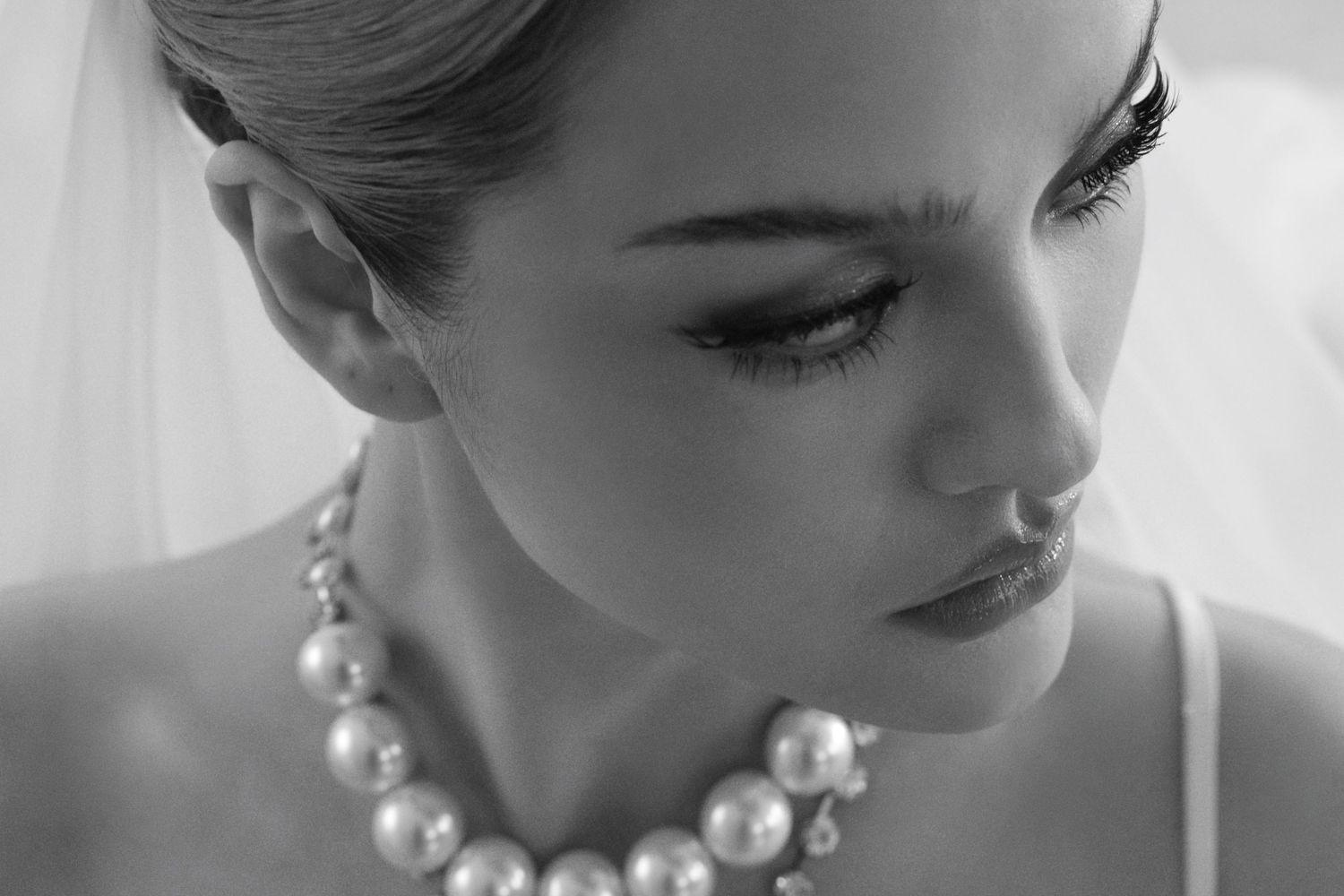 Black and white bridal portrait featuring a bride wearing a pearl necklace and veil.