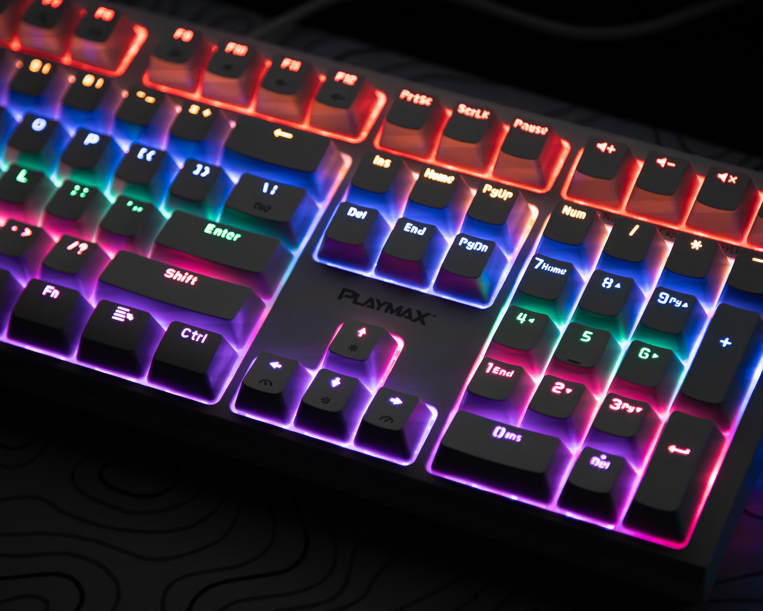 Colorful RGB illuminated mechanical gaming keyboard with rainbow backlit keys on dark surface.