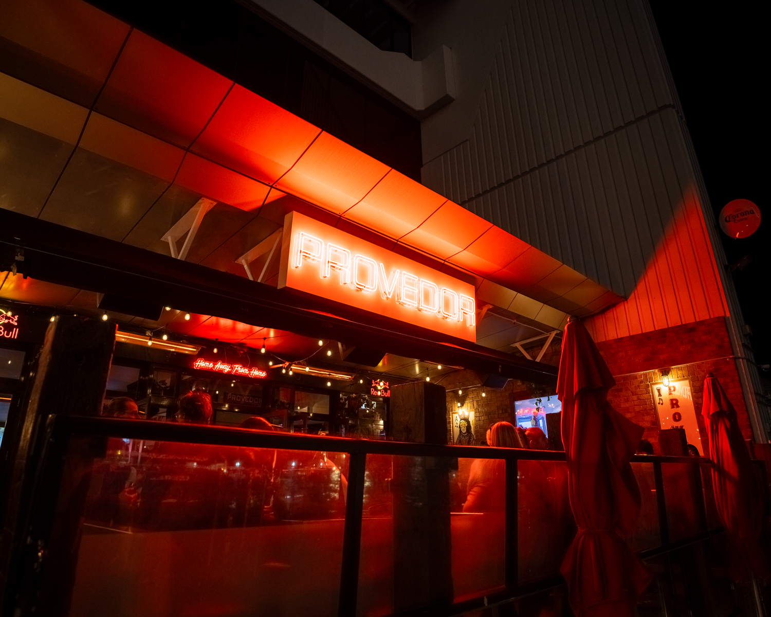 Provedor restaurant exterior at night with glowing red neon sign and warm ambient lighting.