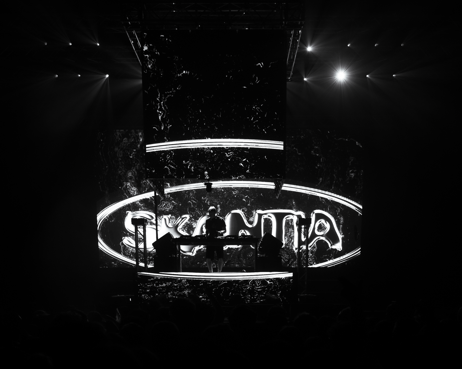 Black and white neon sign glowing in the dark at a live music venue or nightclub event.