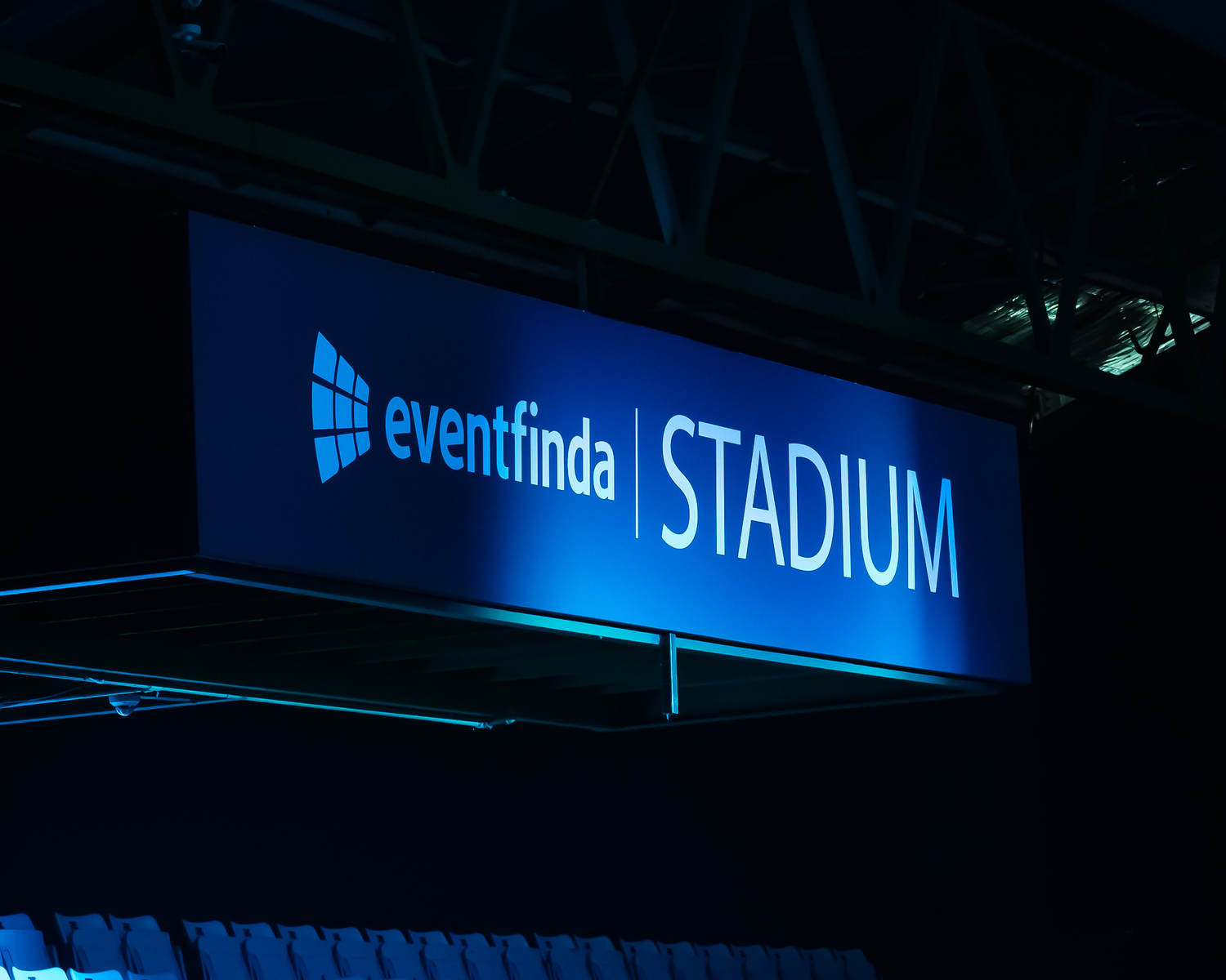 Illuminated Eventfinda Stadium sign glowing blue inside a sports and entertainment venue.