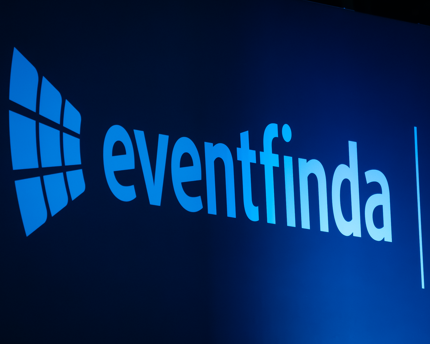 Bright blue Eventfinda logo displayed on a large illuminated screen in a dark venue.