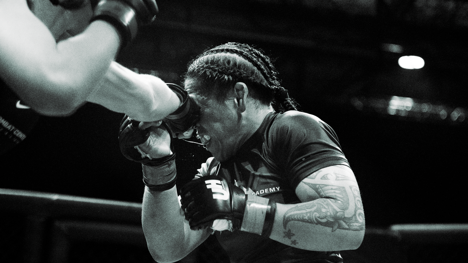 Black and white close-up of a focused boxer in defensive stance during a ring match.