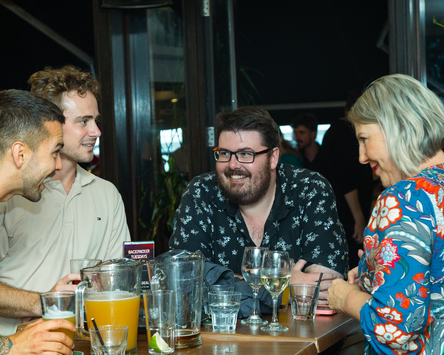 Group of friends laughing and enjoying drinks together at a restaurant table.