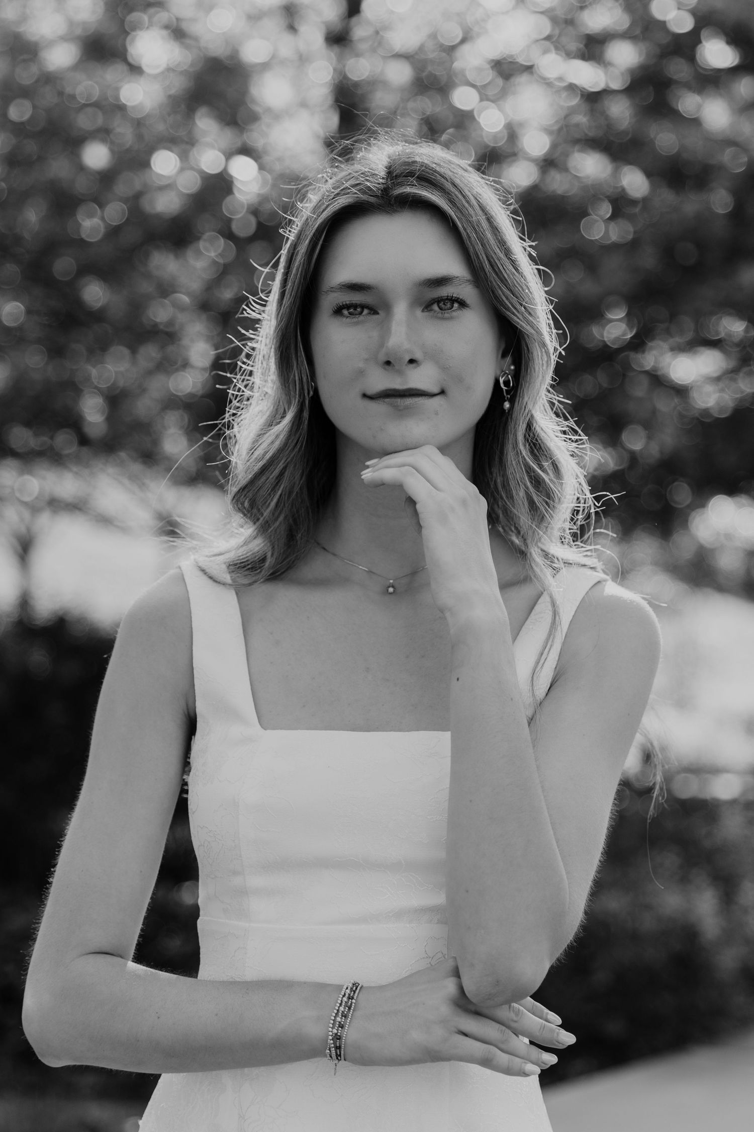 Monochrome portraits showing a white sleeveless top against a blurred natural background.