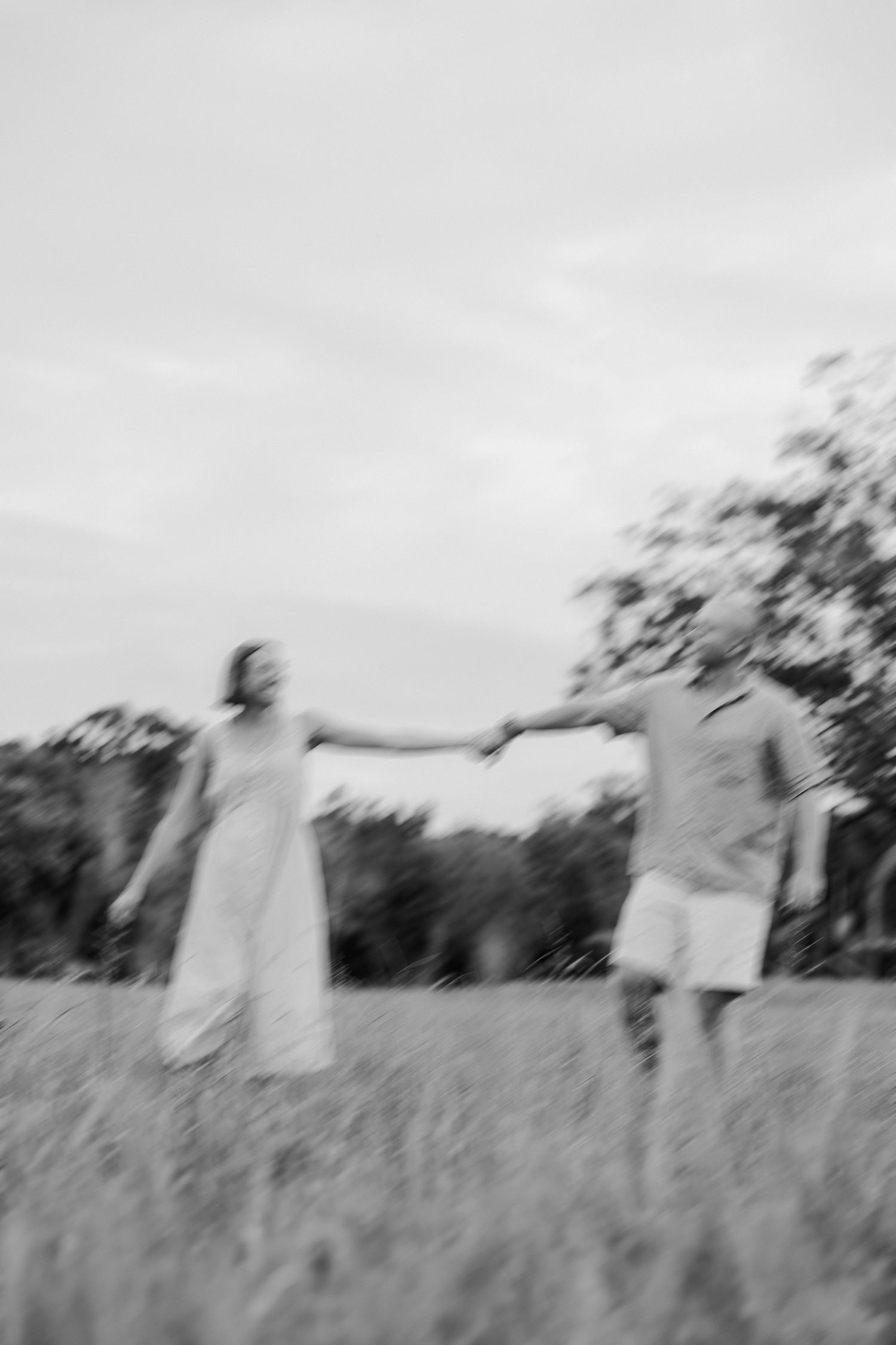 A blurred motion photo of two people holding hands in a grassy field.