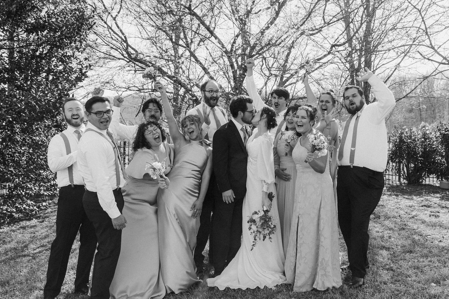Wedding party poses together for a black and white group photo outdoors.