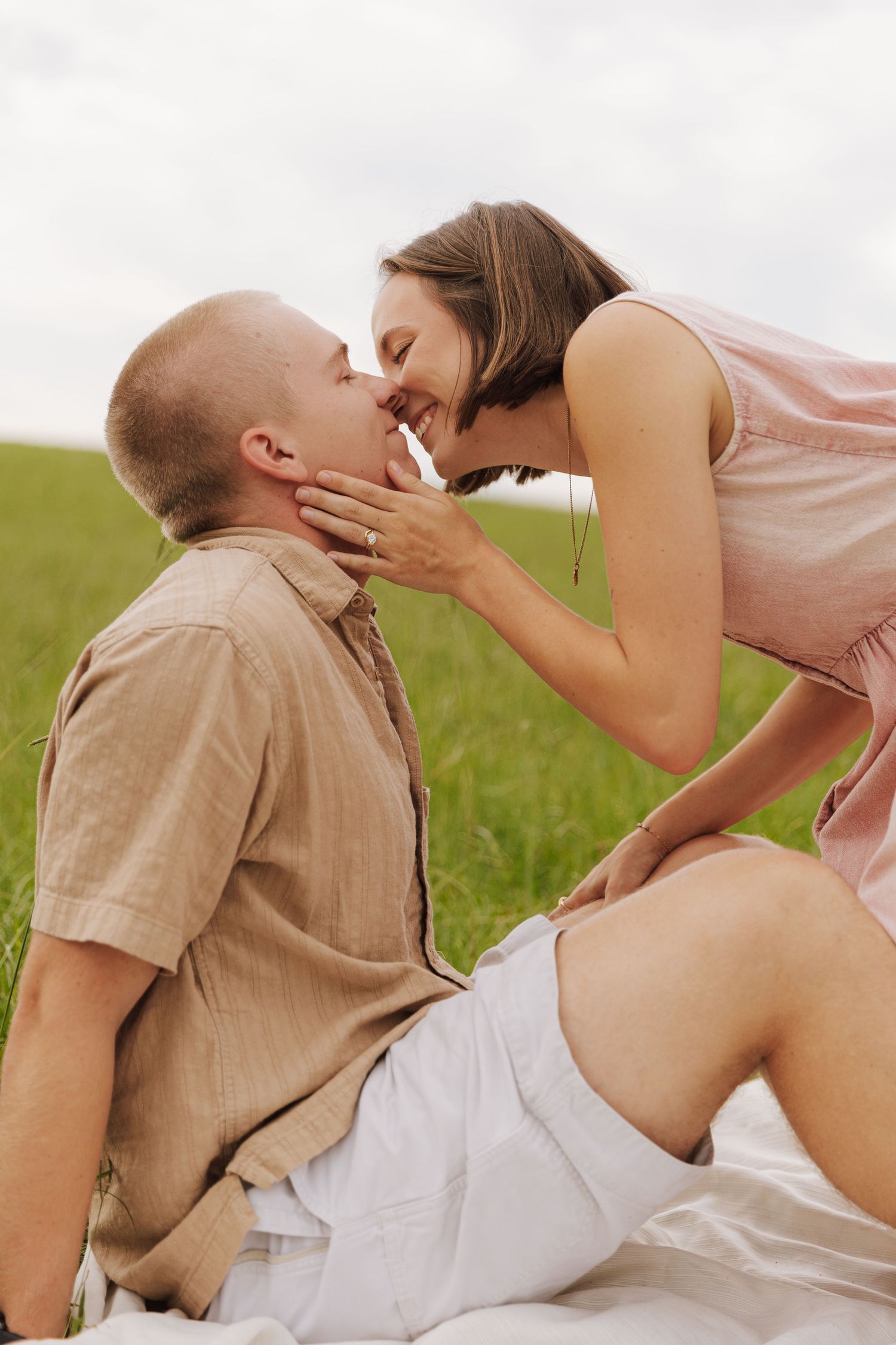 A romantic moment between a couple sitting on a blanket in a summer meadow.