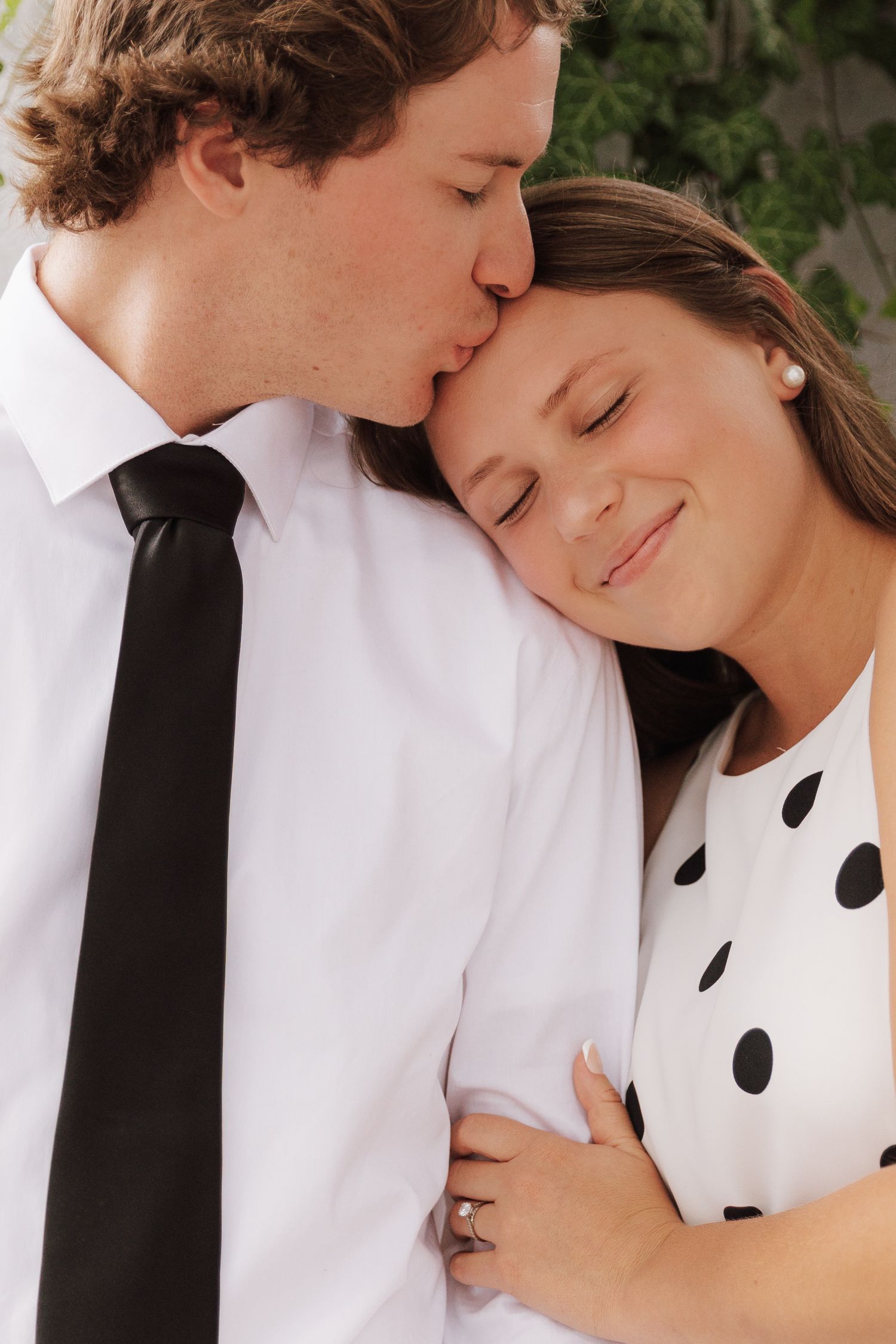 A couple in black and white formal attire share a tender embrace.