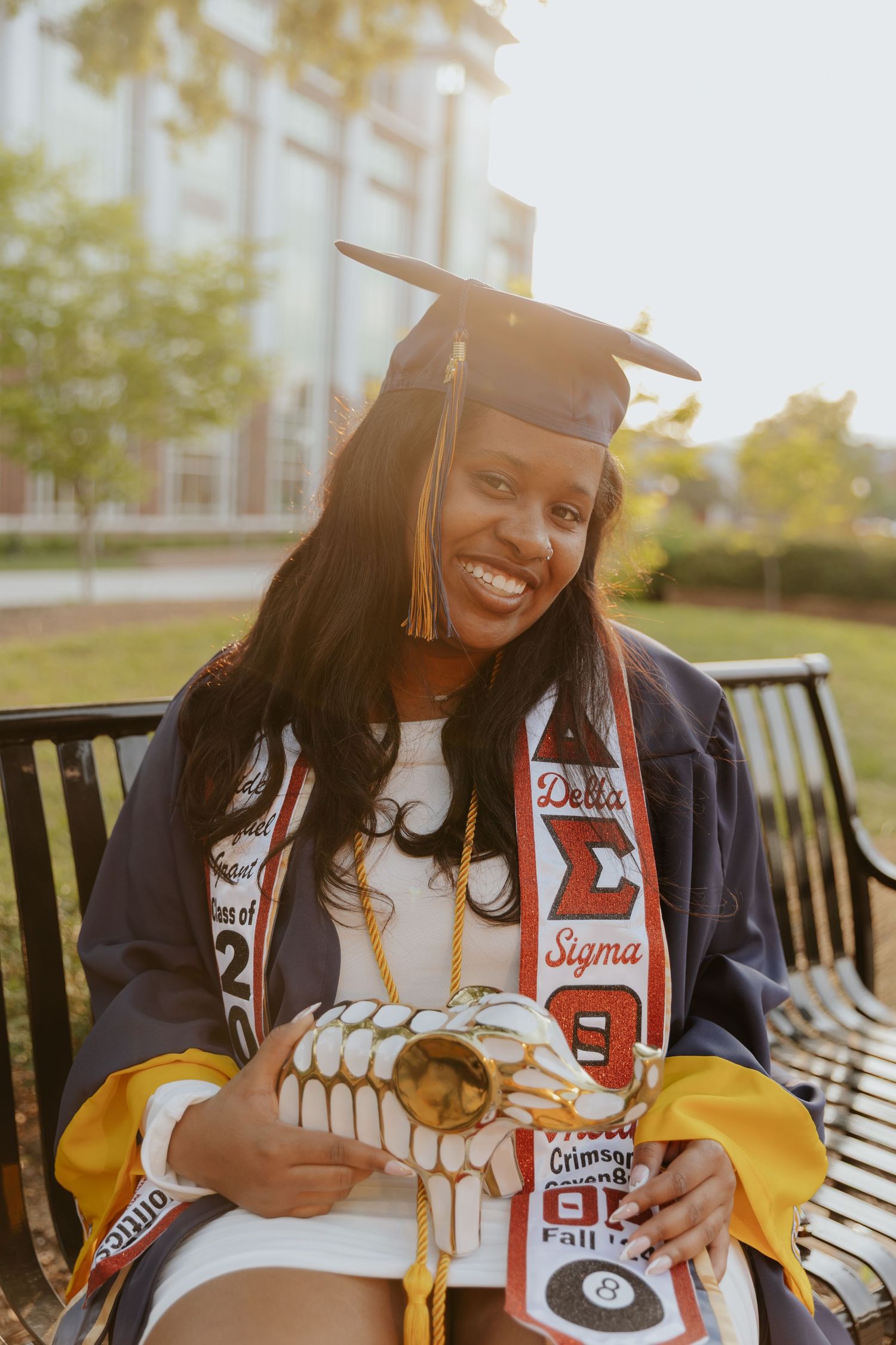 A graduate in cap and gown with Delta Sigma Theta sorority stoles celebrates on campus.