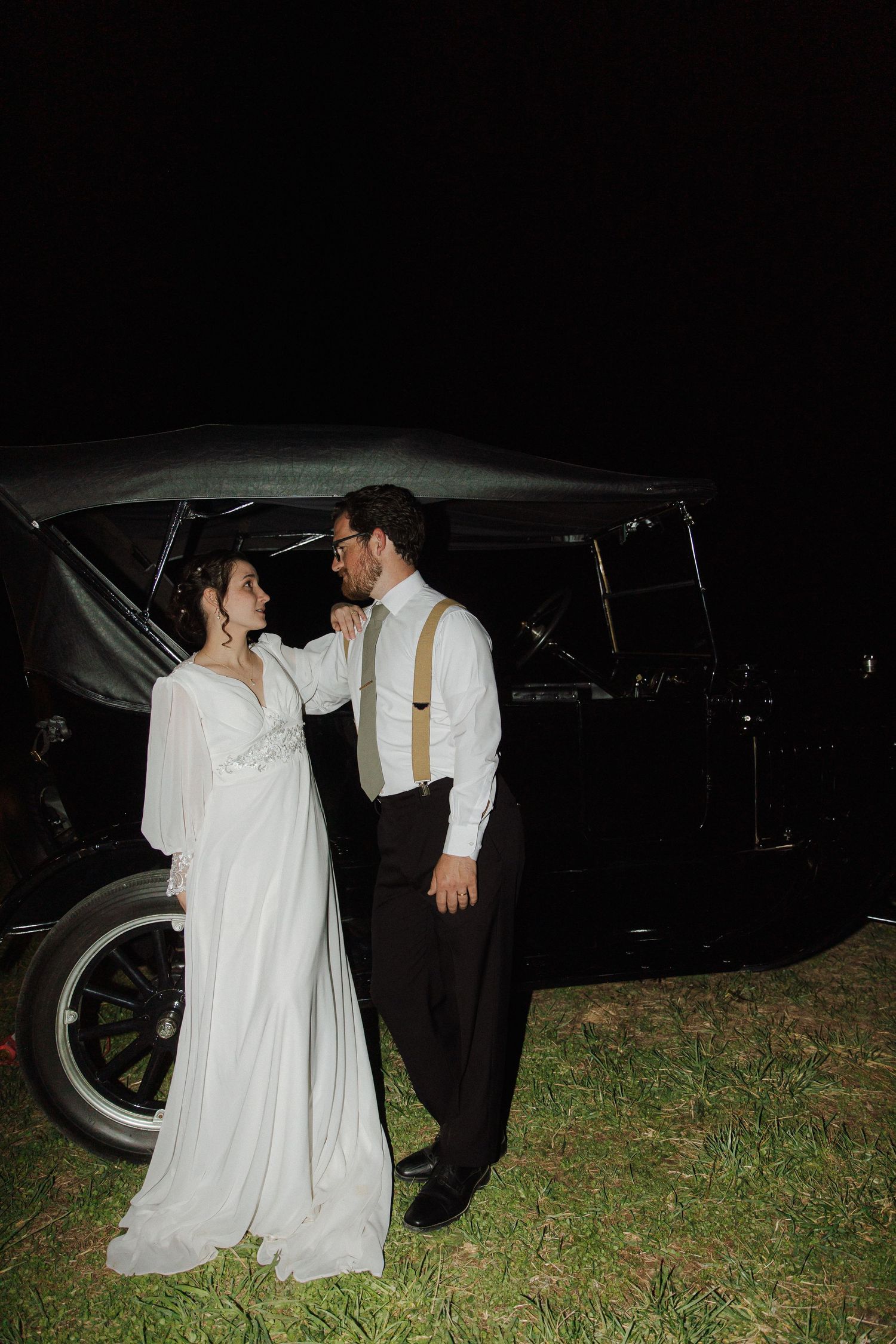 Nighttime wedding photos with vintage car and elegant formal attire.