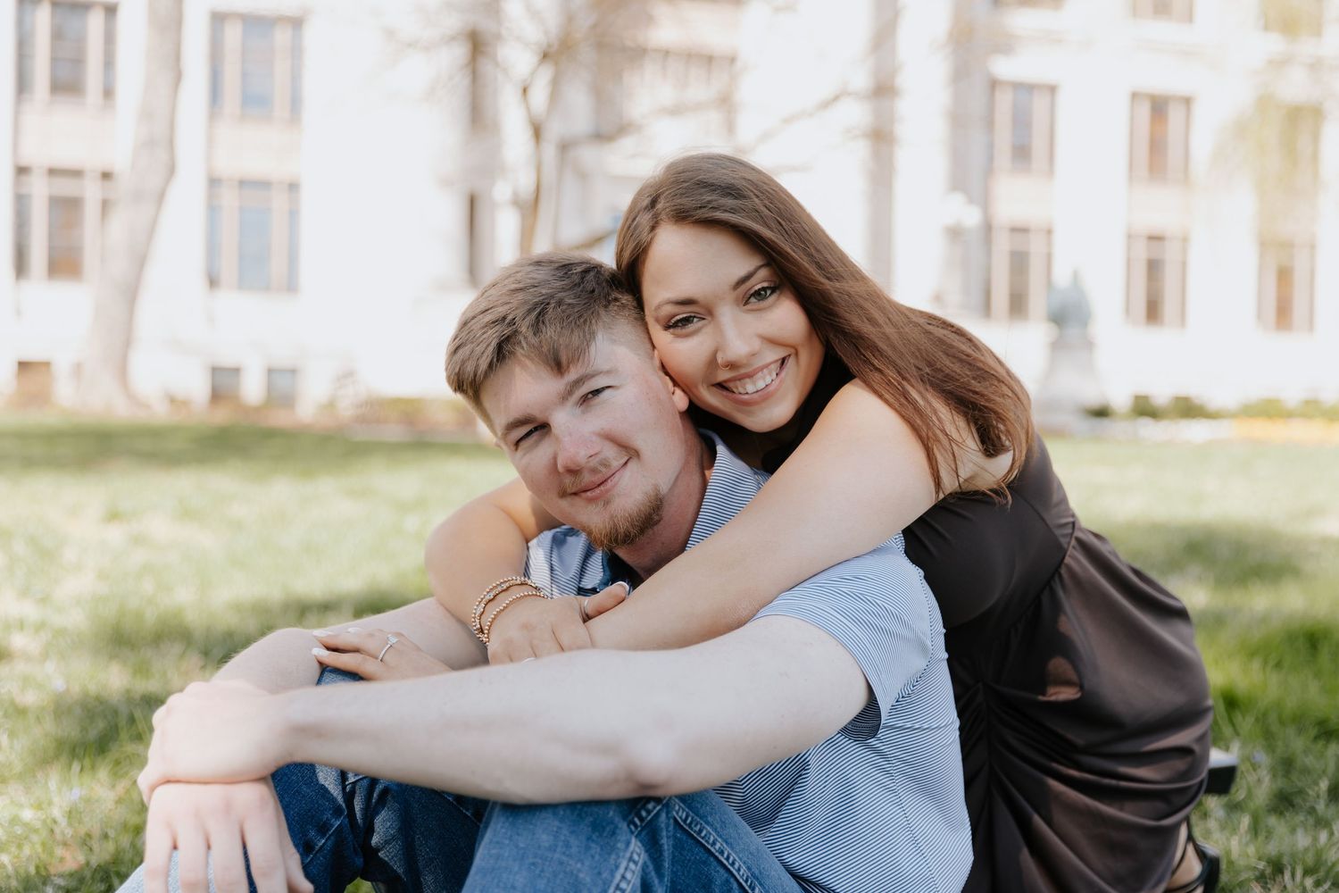 Romantic couple embraces tenderly while sitting together in a park during sunset.