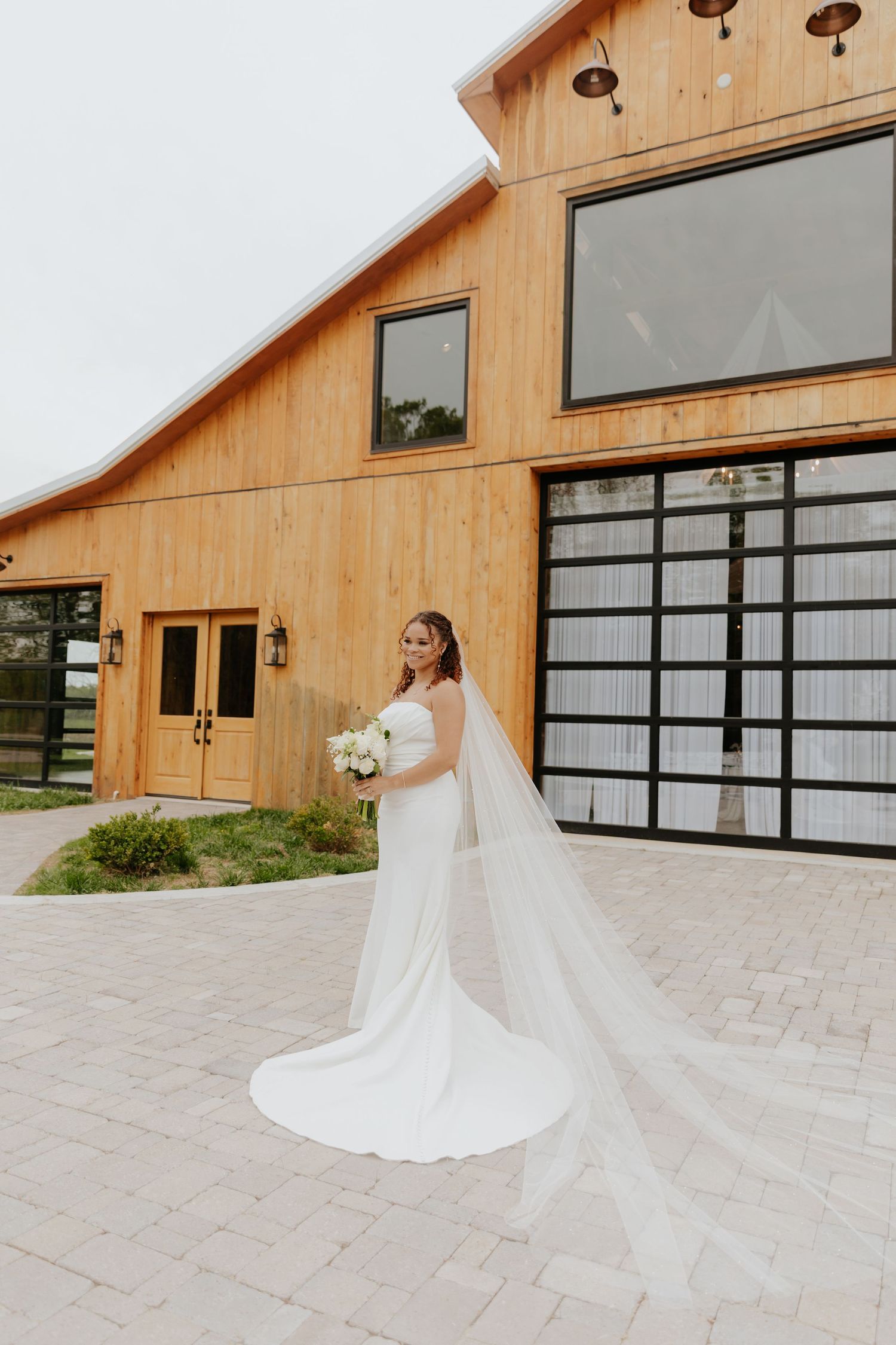 Modern barn venue with glass garage doors and stone paved courtyard.