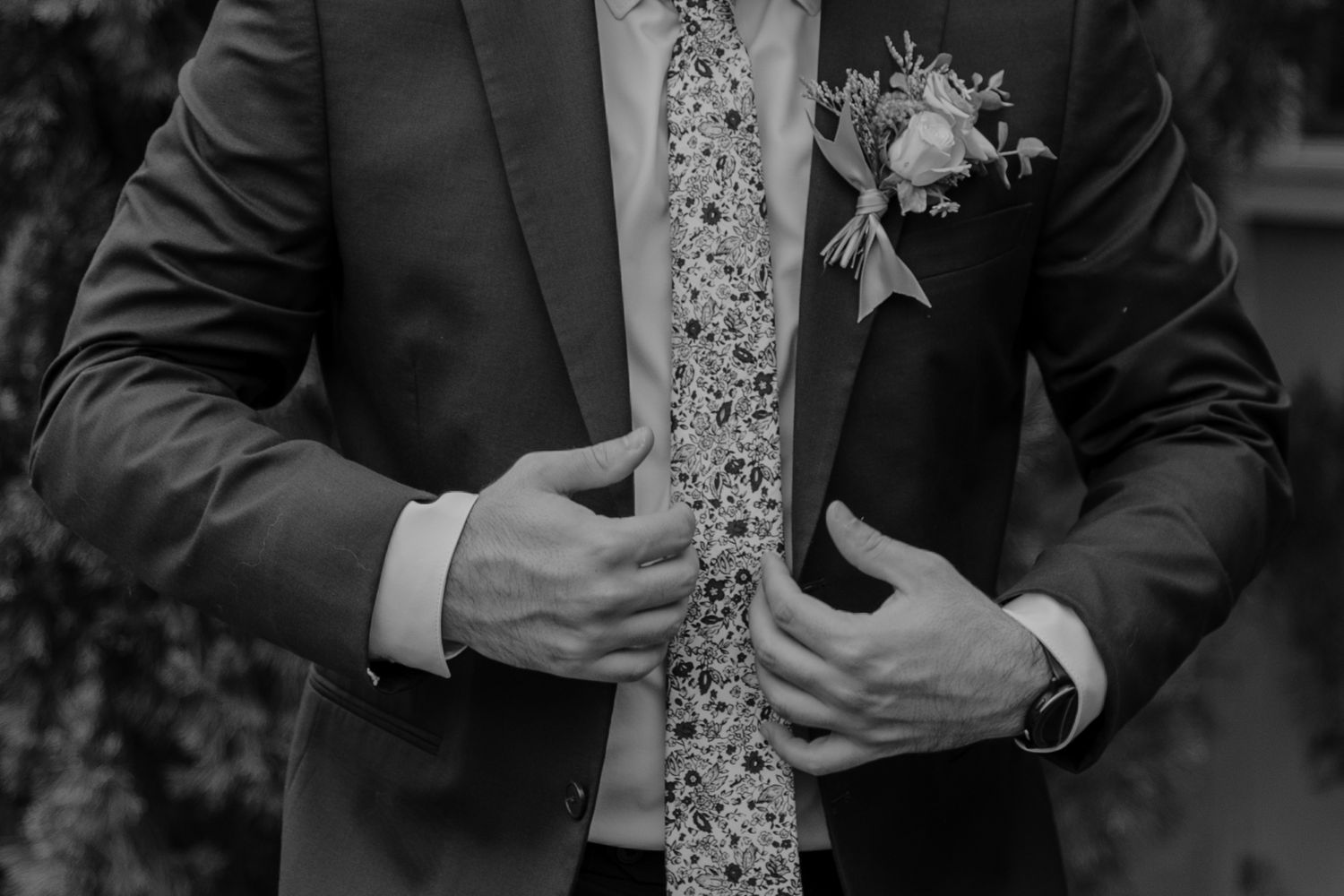 Groomsmen in dark suits with floral ties preparing for wedding ceremony.