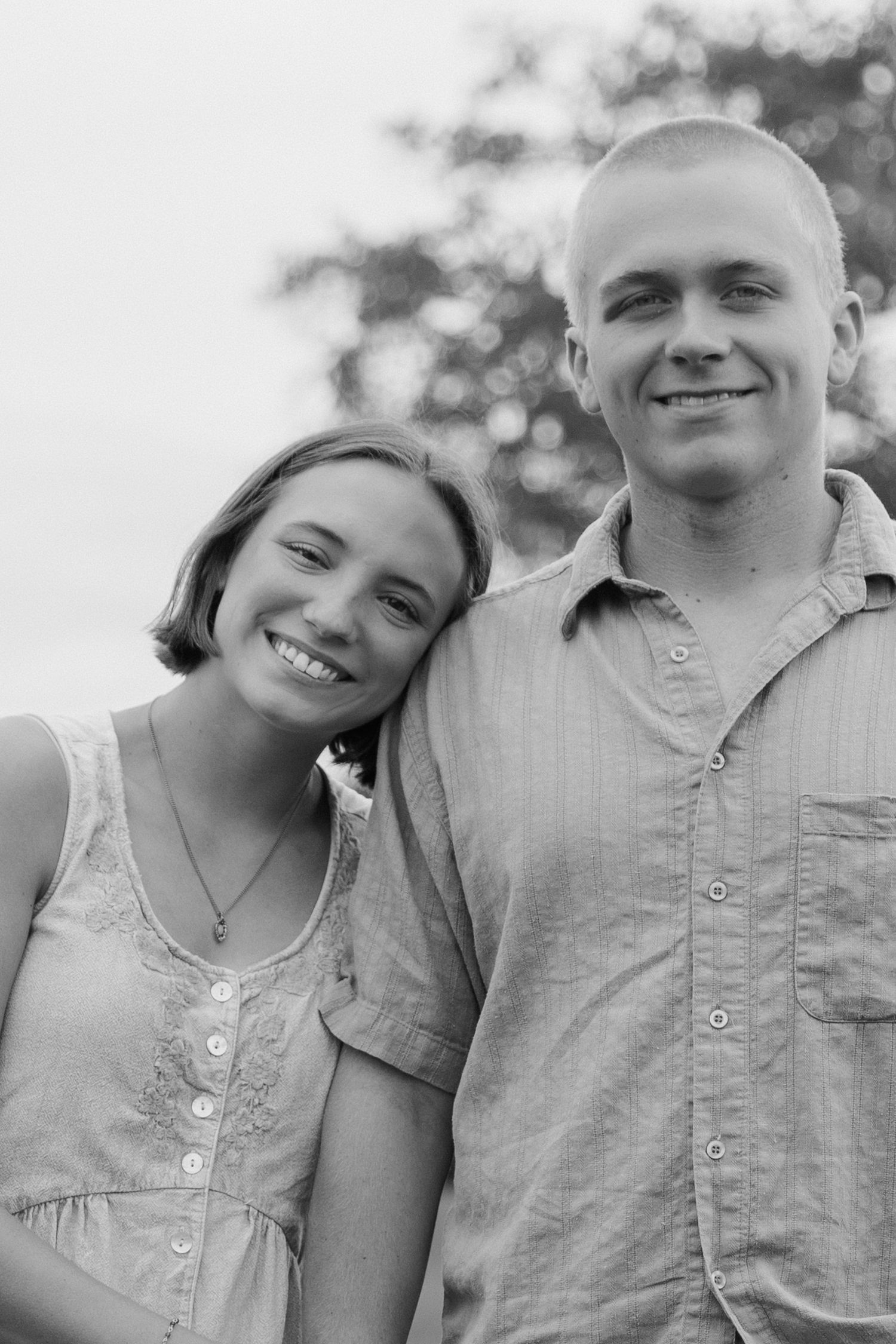 A couple shares a joyful moment together outdoors in black and white.