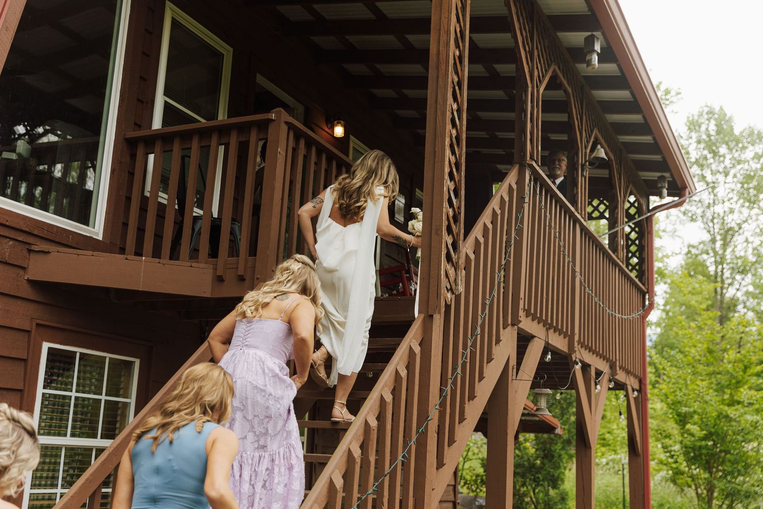 People climbing wooden stairs at a rustic cabin venue surrounded by trees.