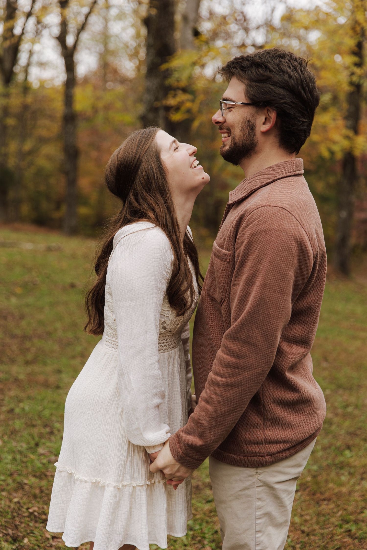 A romantic couple shares a tender moment in an autumn forest setting.