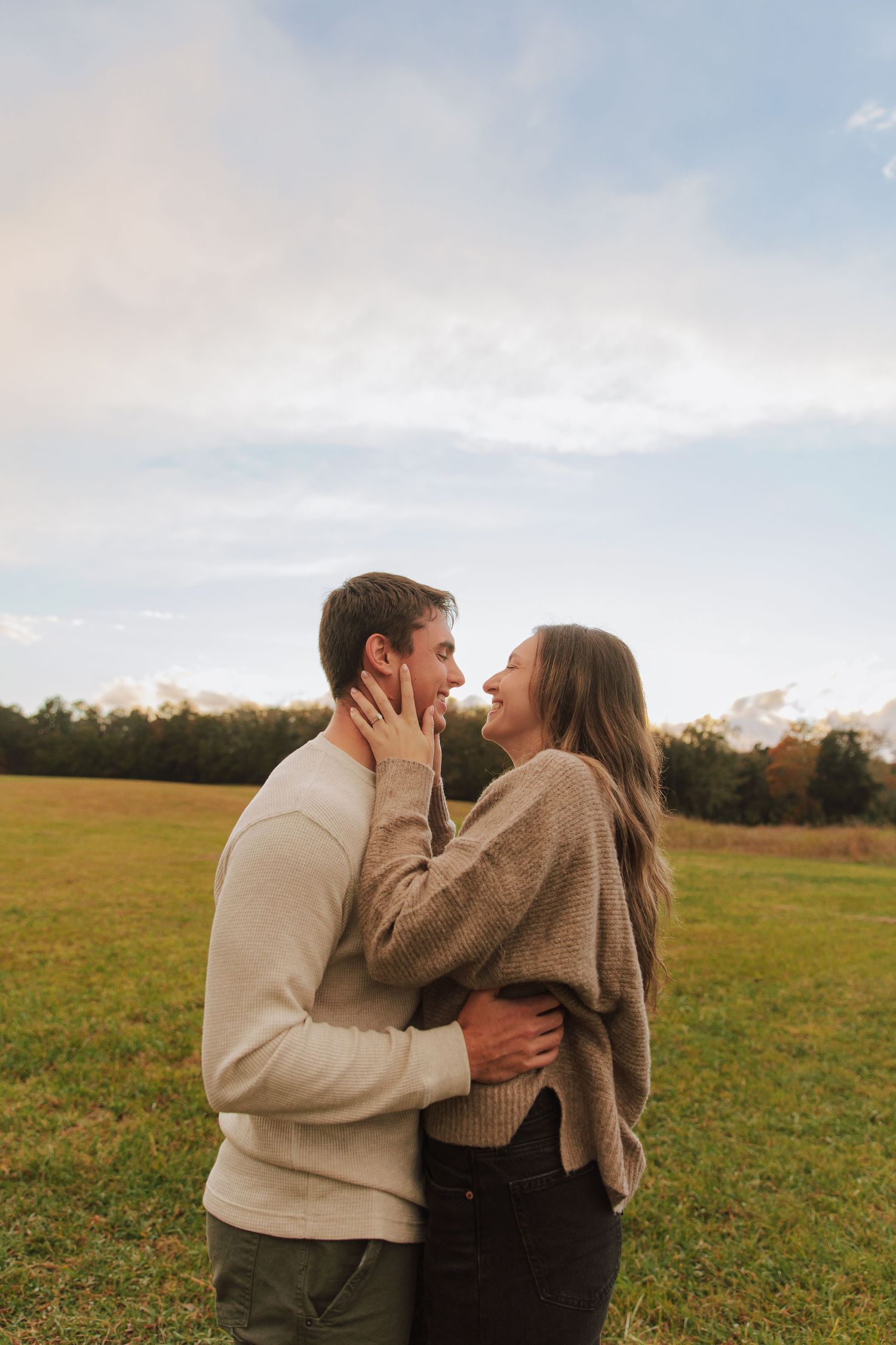 A romantic couple embracing in a golden field during sunset.