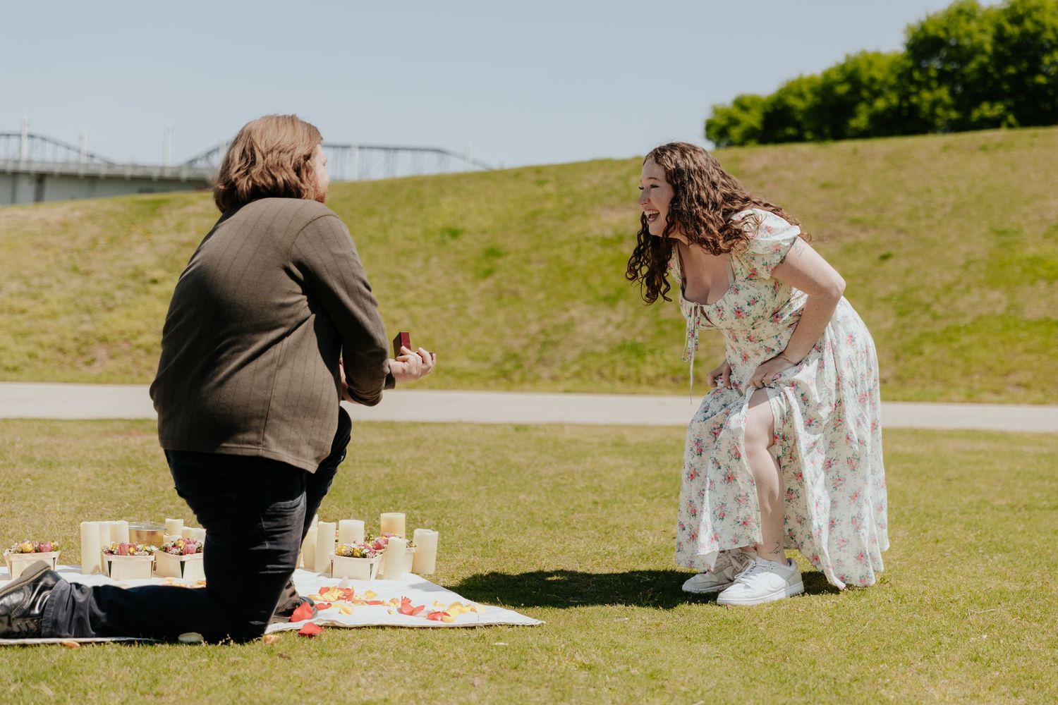 A couple enjoys a romantic picnic on a grassy hillside during a sunny afternoon.