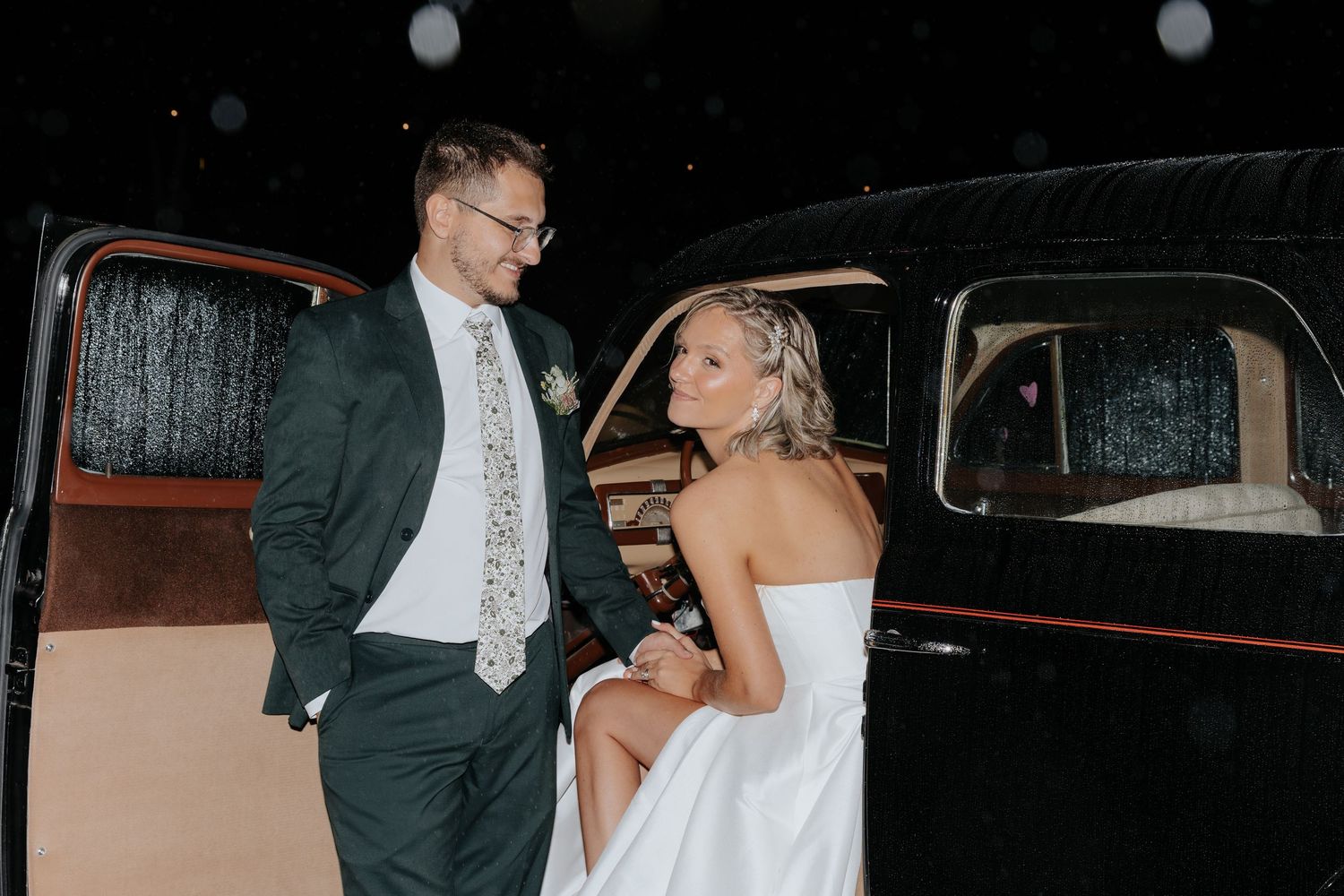 Bride and groom in vintage car before exiting wedding.
