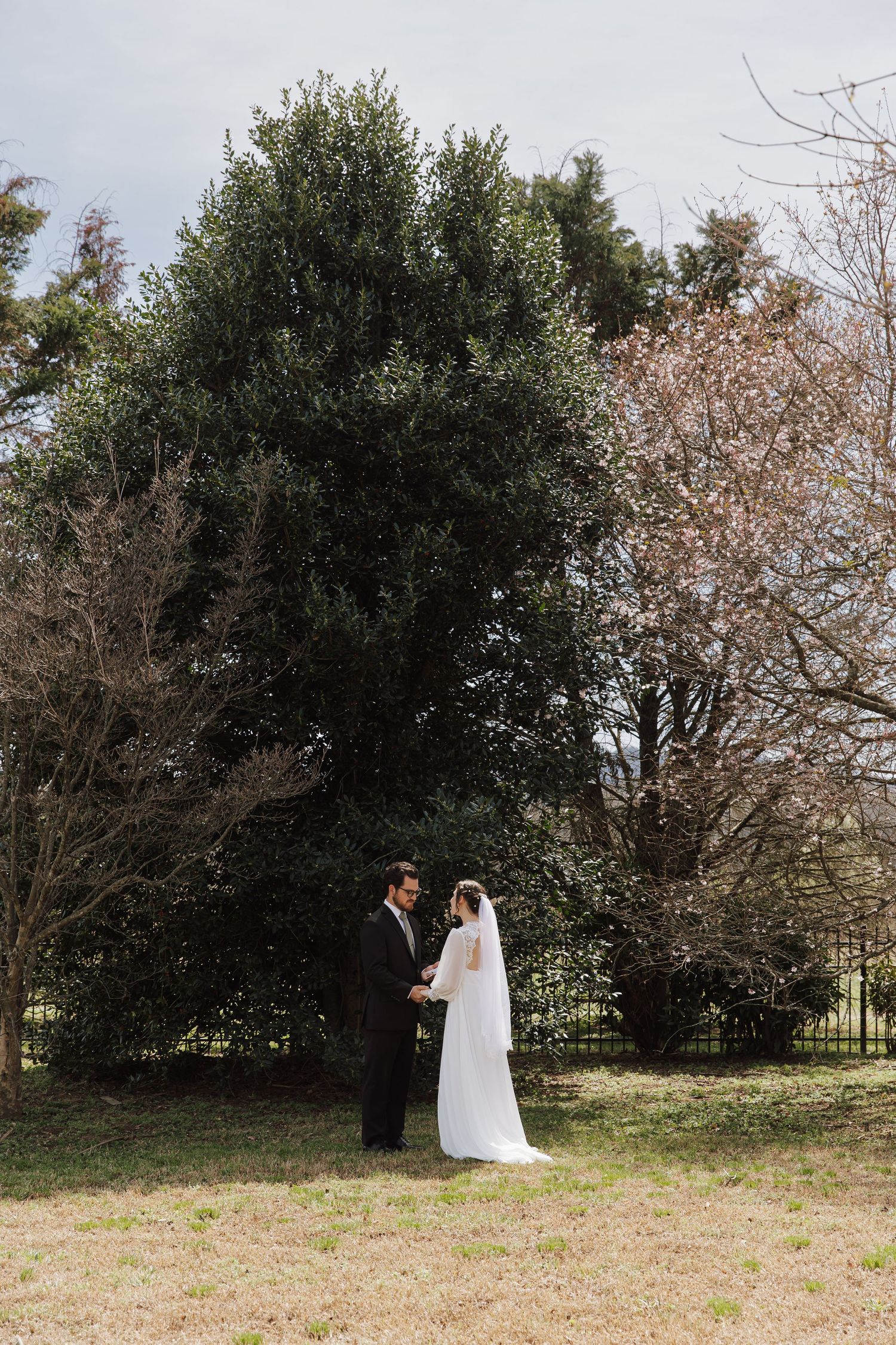 Bride and groom hold hands in a lush garden setting on their wedding day.