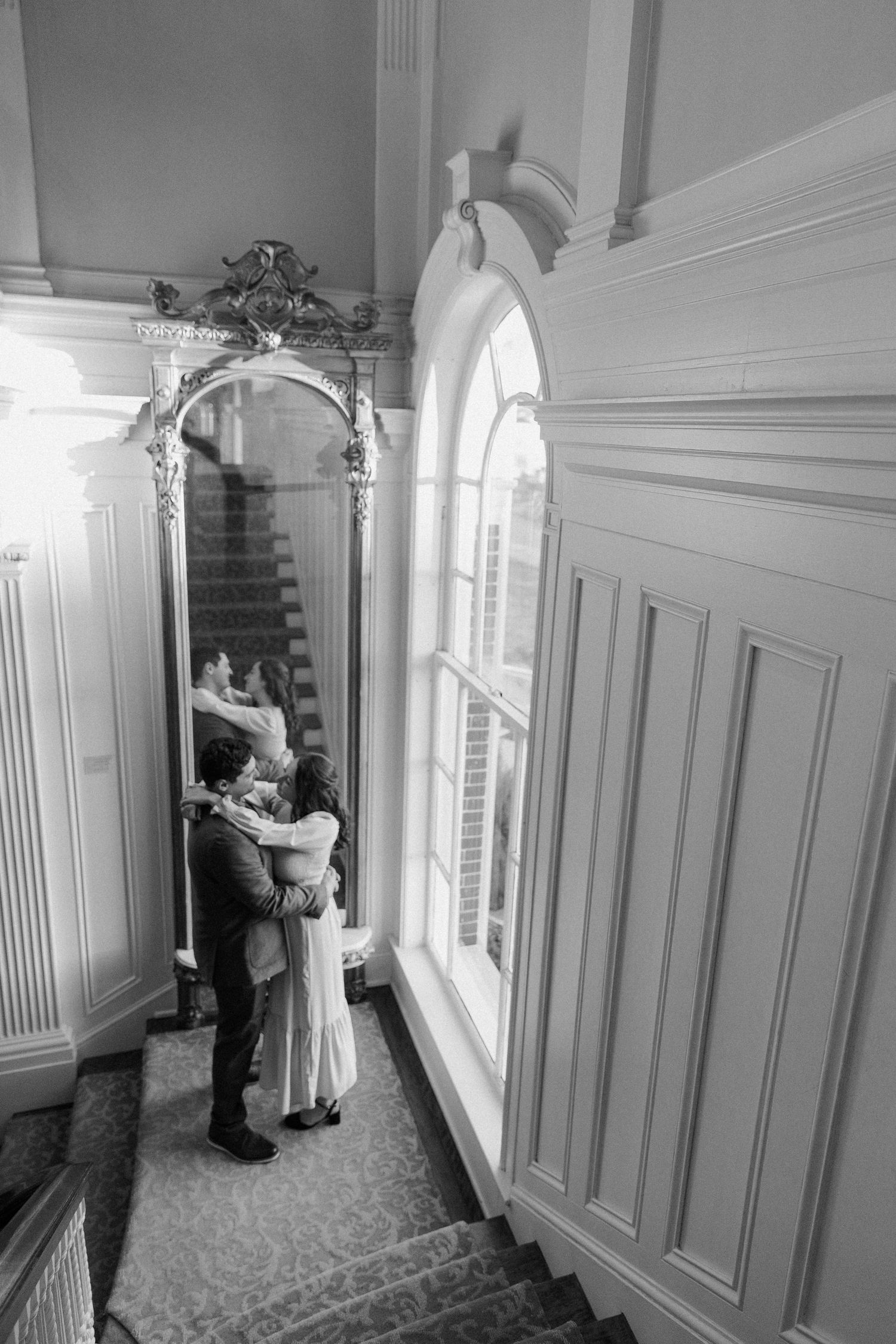 A couple shares a dance near bright windows in a classic interior.