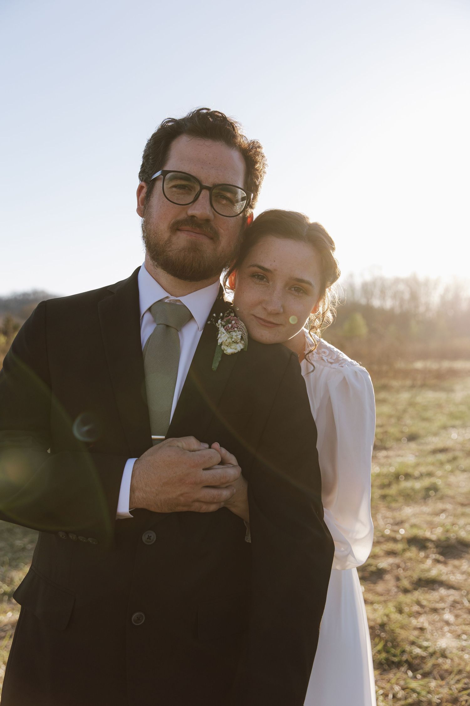 A couple shares an intimate moment at sunset in an outdoor setting.