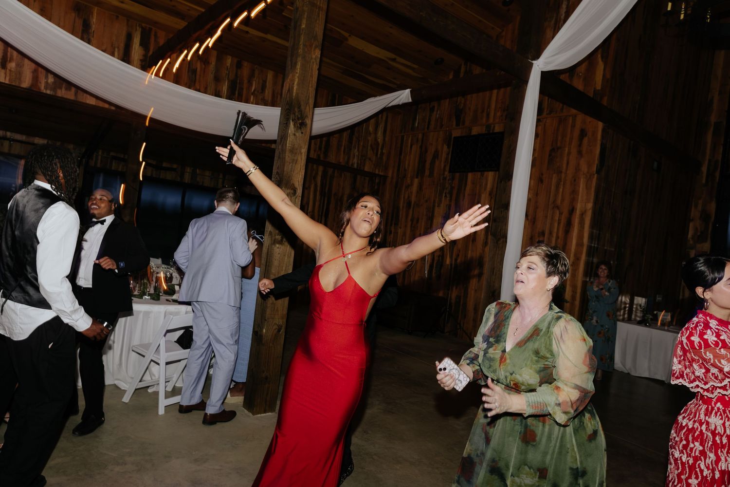 Wedding reception dance party in rustic barn with string lights.