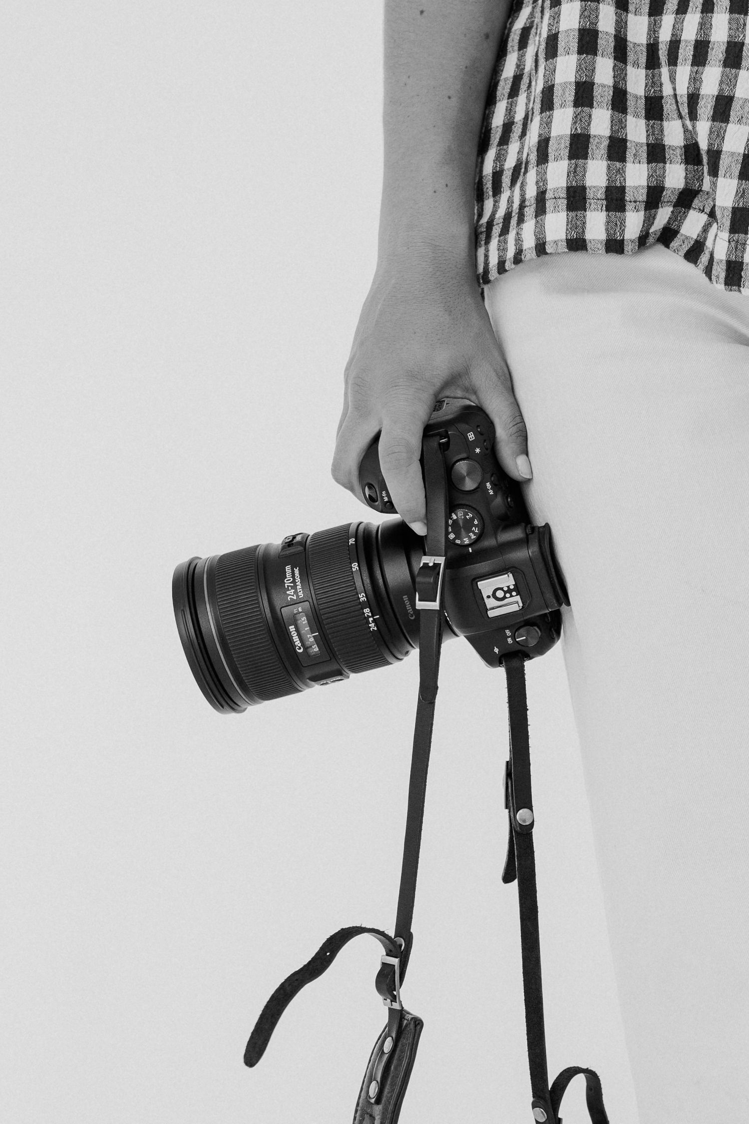 Close-up shots of hands holding a professional DSLR camera with a telephoto lens.
