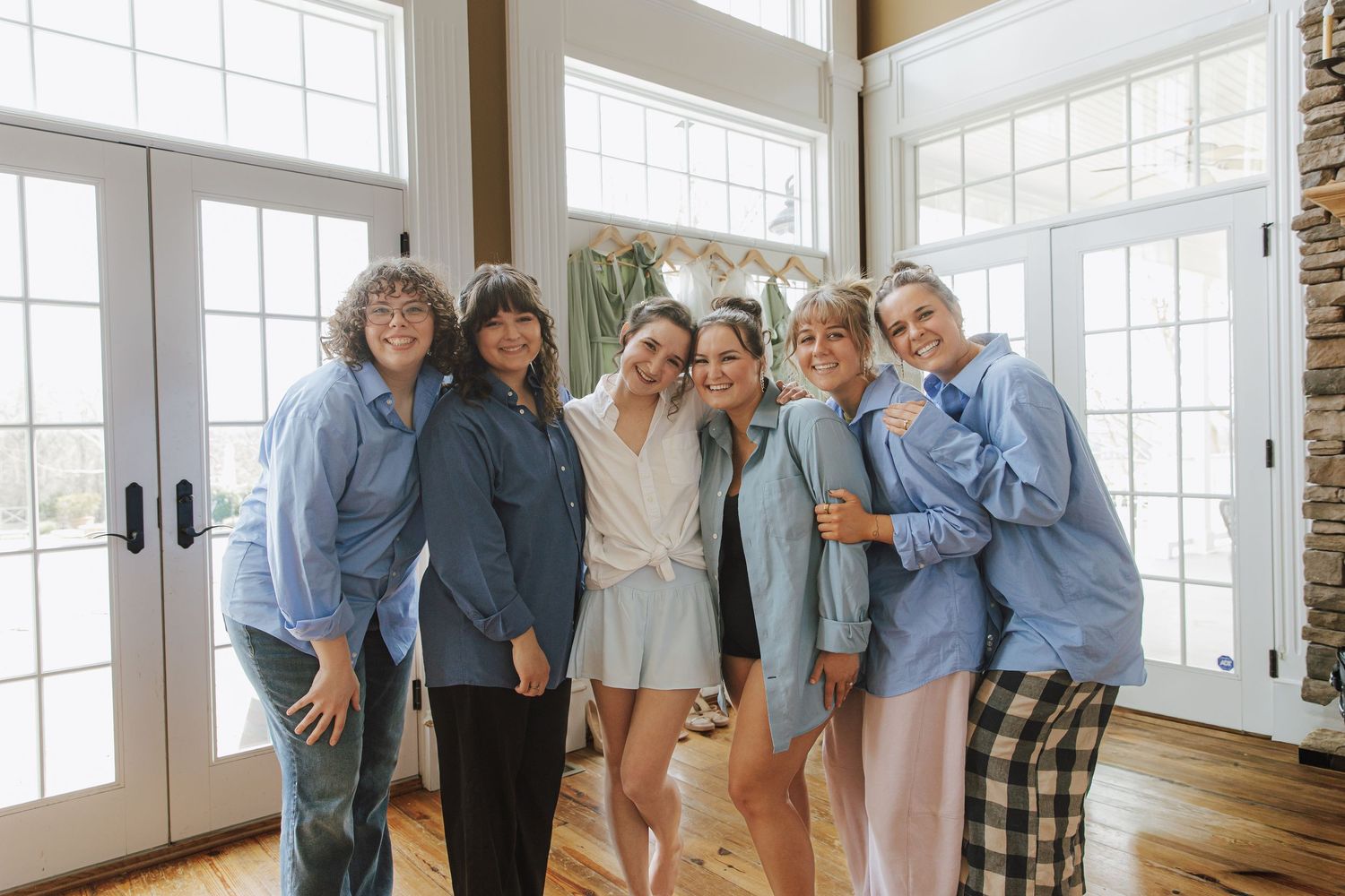 A group poses together in a bright sunlit room with large windows.