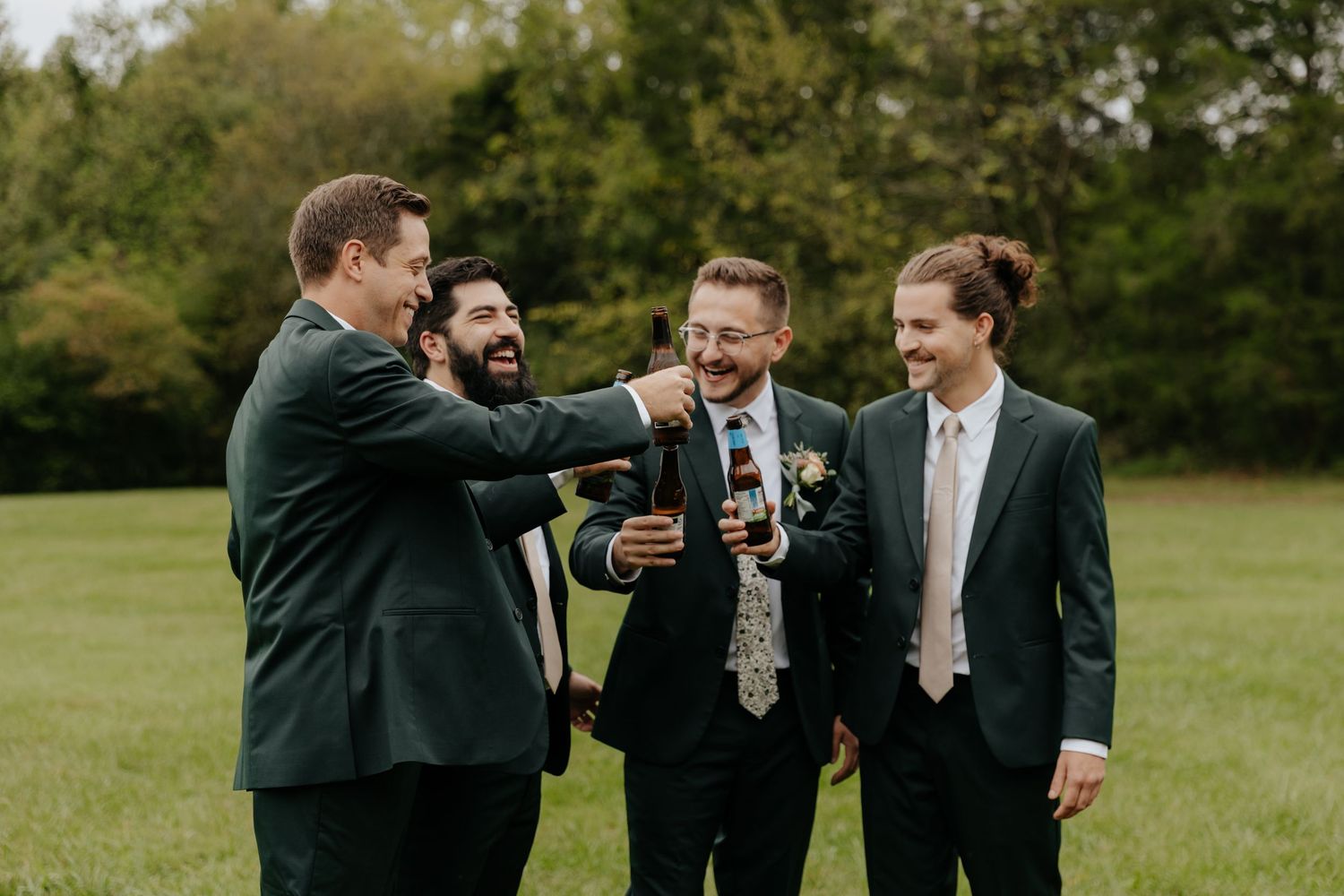Group of groomsmen laughing together outdoors in formal attire.