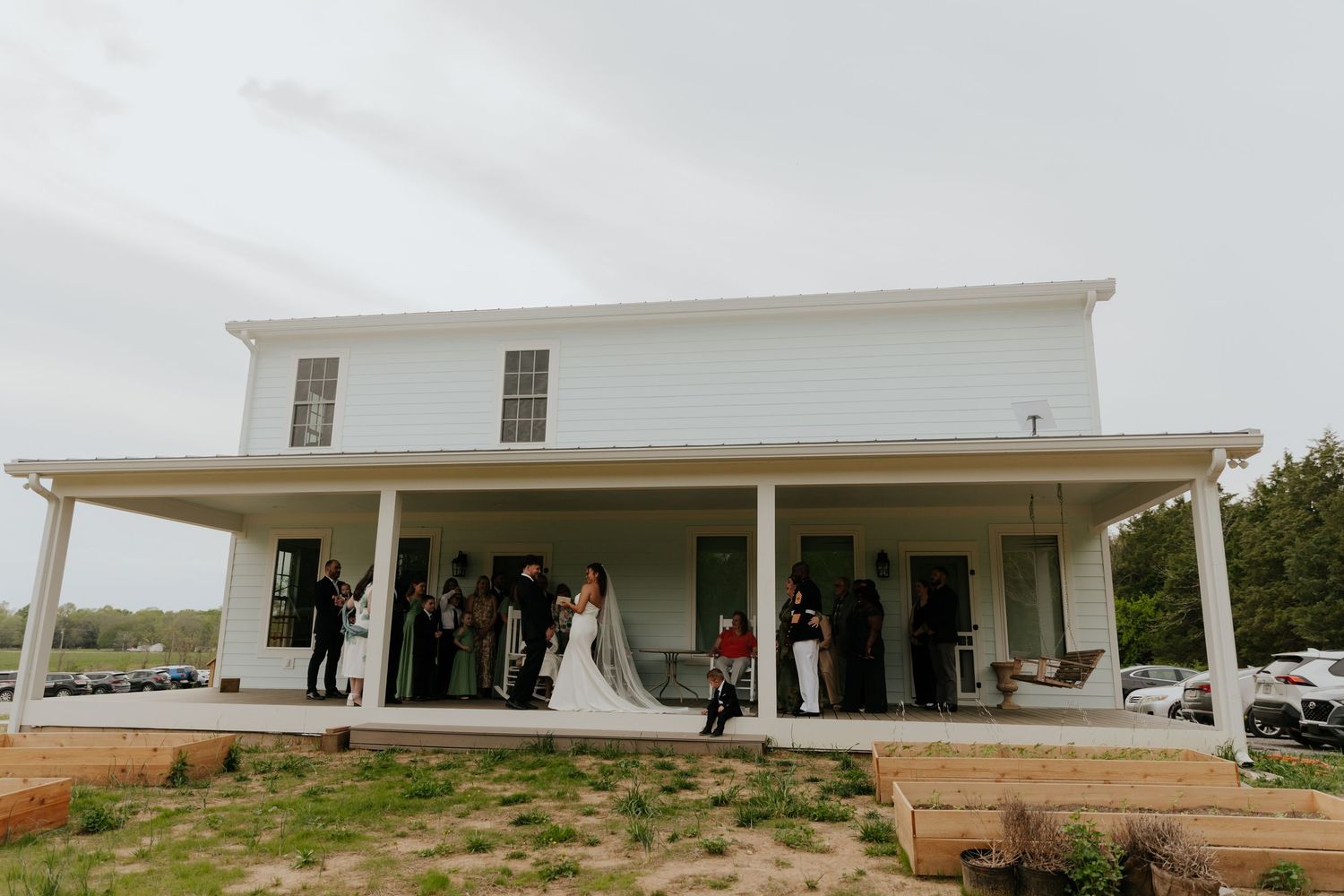 Modern white farmhouse style venue with covered porch and parking area.