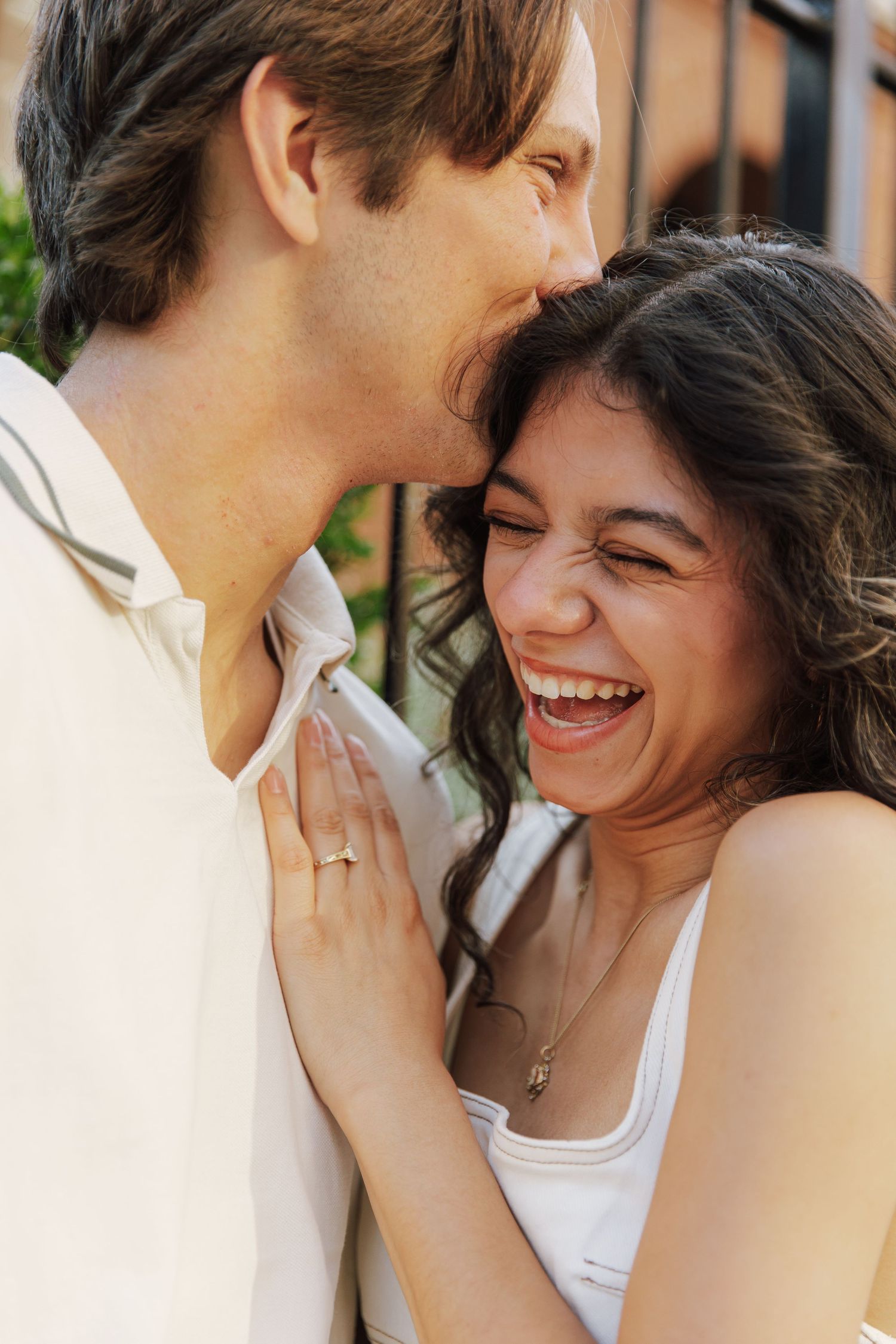A happy couple sharing an intimate moment, woman laughing joyfully while man whispers in her ear.