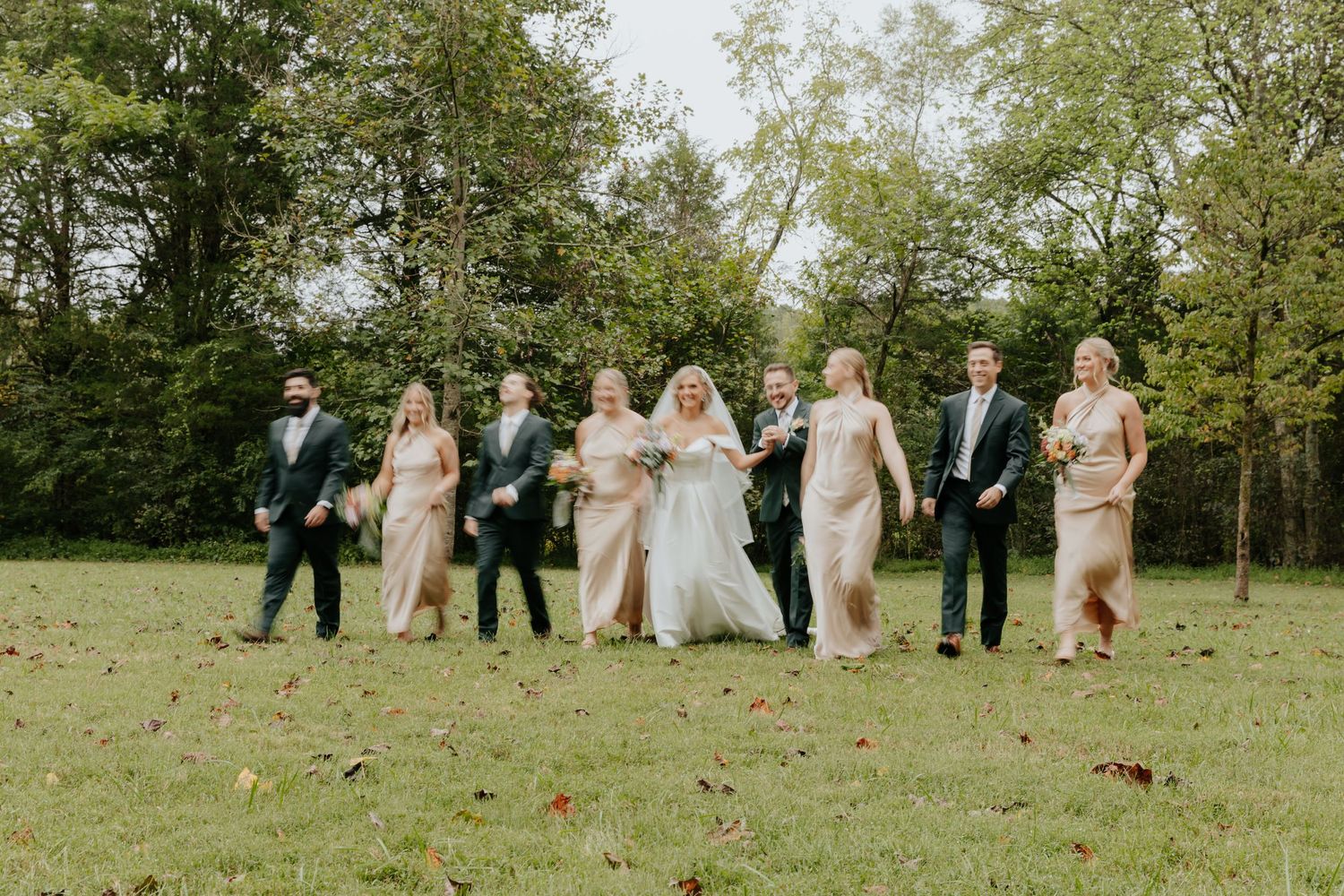 Wedding party walks and laughs together on a grassy lawn at a Tennessee wedding.