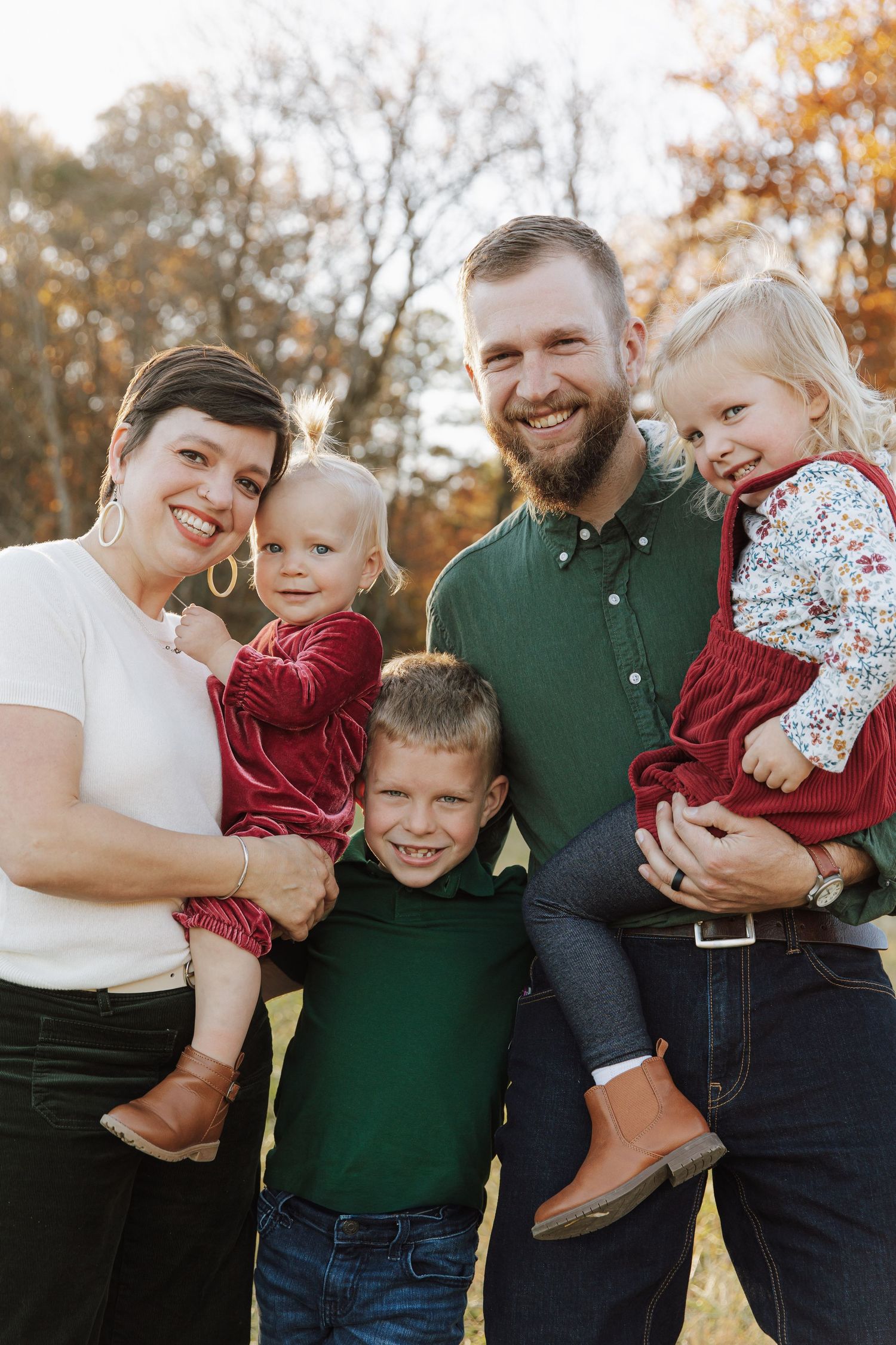 Happy family group hugging and laughing together during autumn photo session.