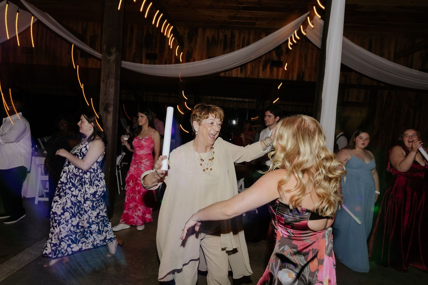 People dancing and celebrating at a reception under draped fabric decorations.
