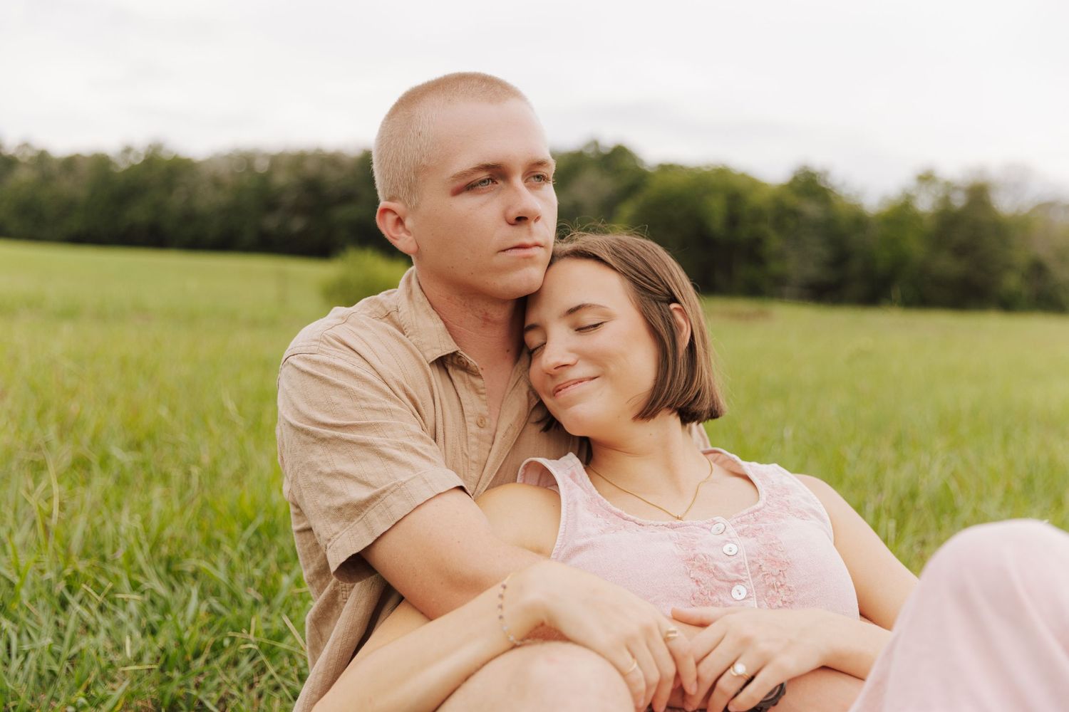 A couple relaxes together in a sunny green field during summer.
