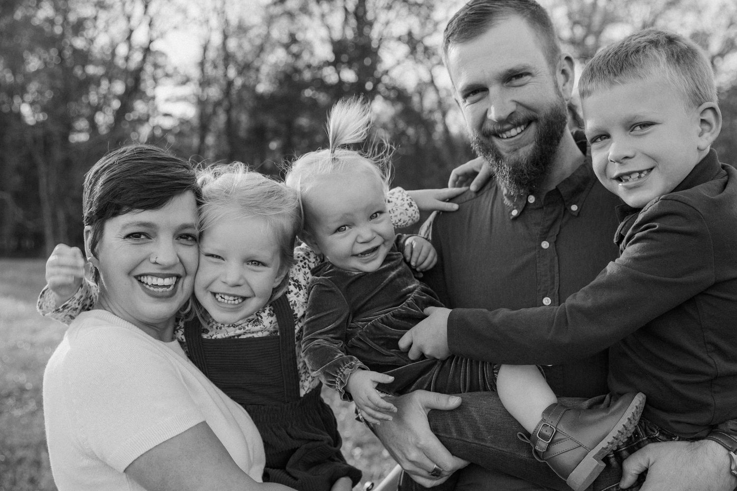 A series of black and white candid family photos showing joyful moments and laughter during an outdoor photo session.