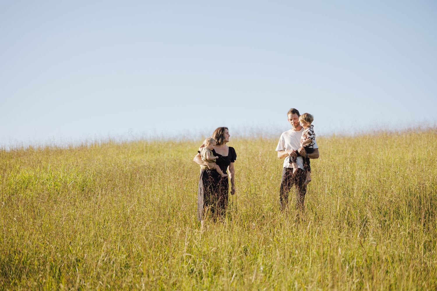 People walking through a golden prairie field on a sunny afternoon.