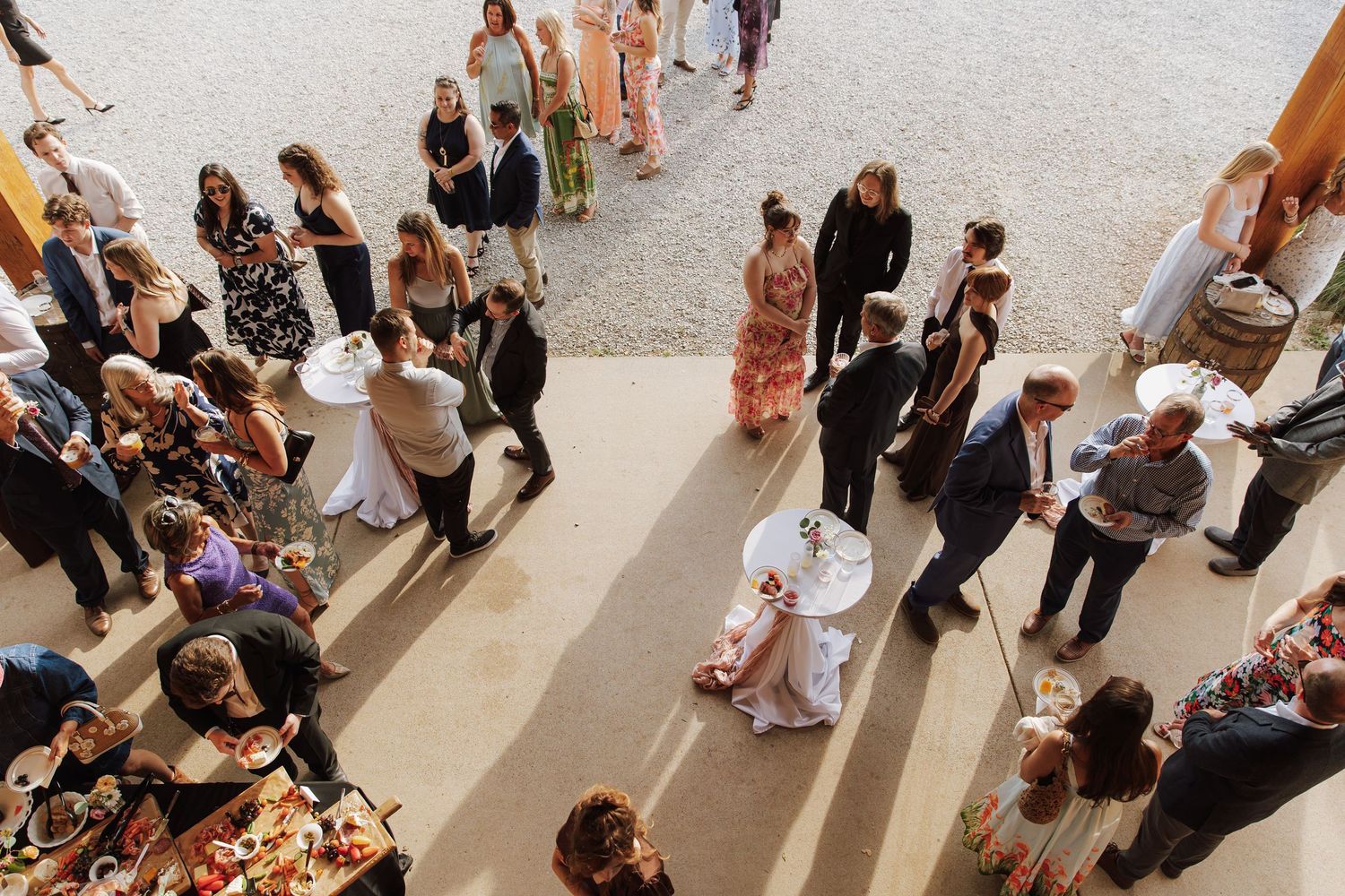 Aerial view of elegantly dressed wedding guests mingling at an outdoor cocktail hour reception.