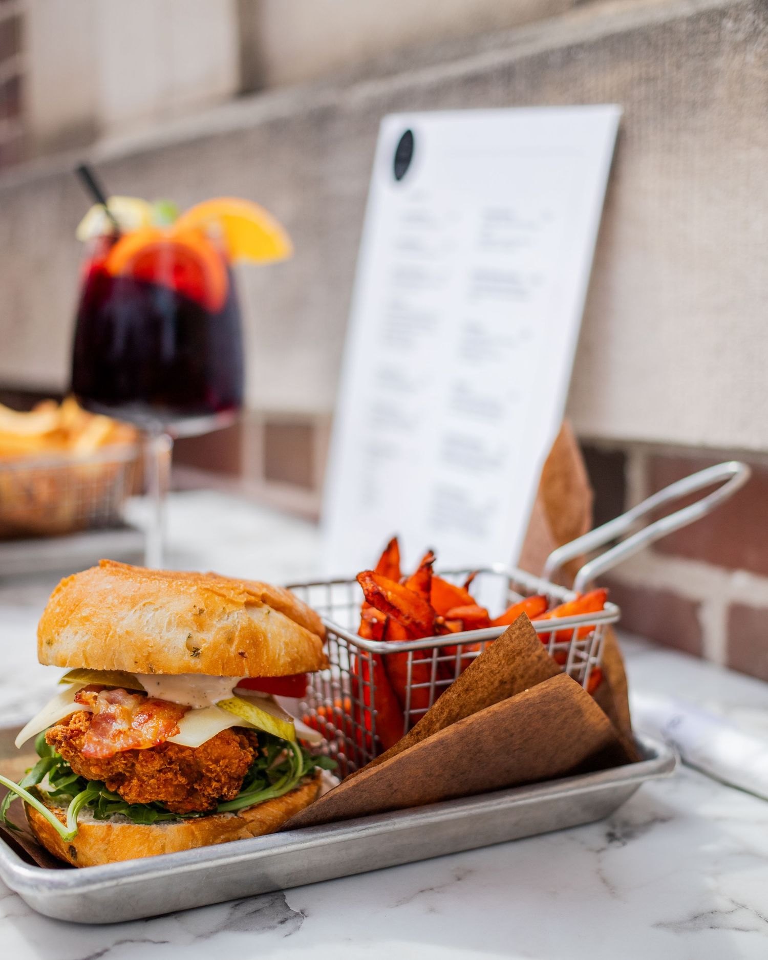 A plate of fried chicken and waffles, accompanied by a glass of orange juice, on a wooden table.