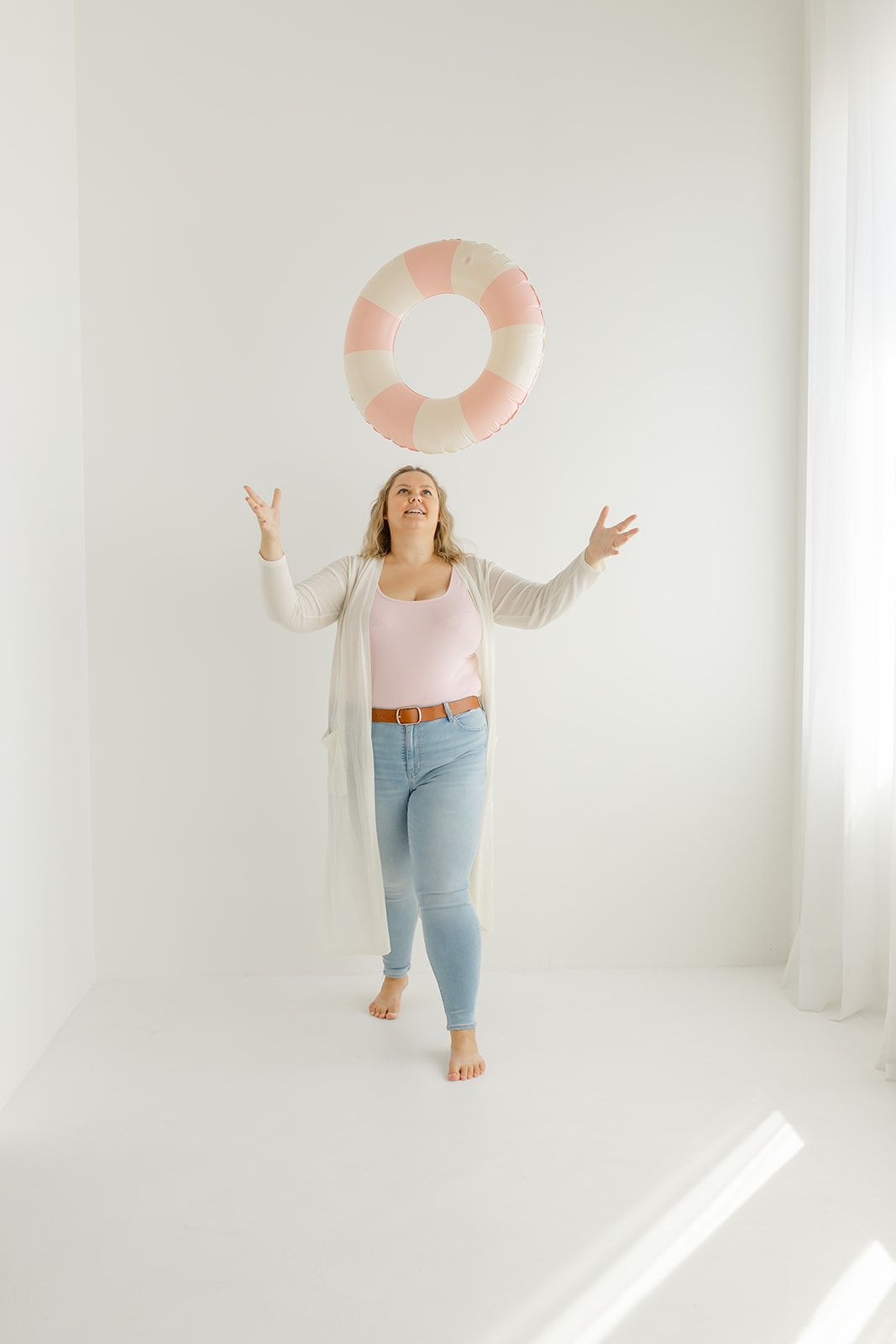 A woman standing and holding a large inflatable ring, appearing to be in a studio or home setting.