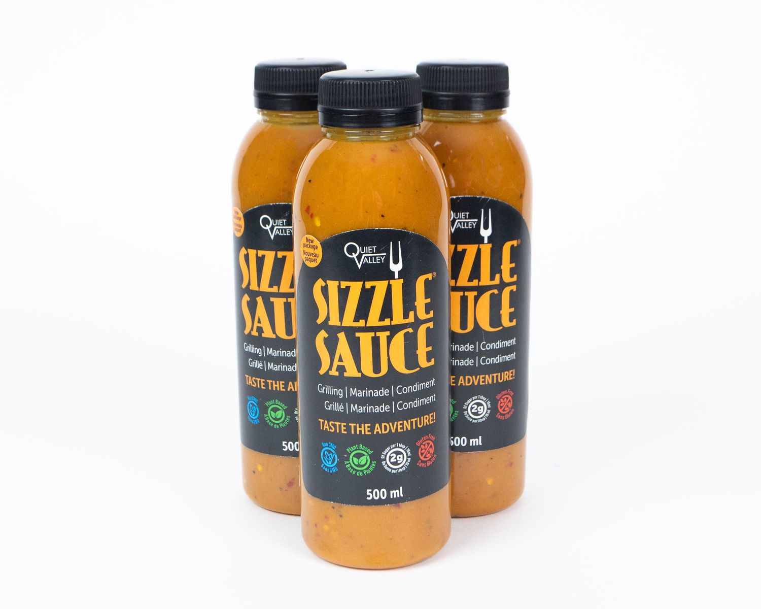 Bottles of orange-colored sauce or dressing on a white background.