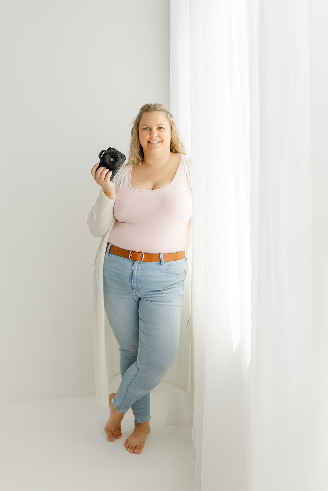 Image of a woman folding clothes in a room with a white wall and window.