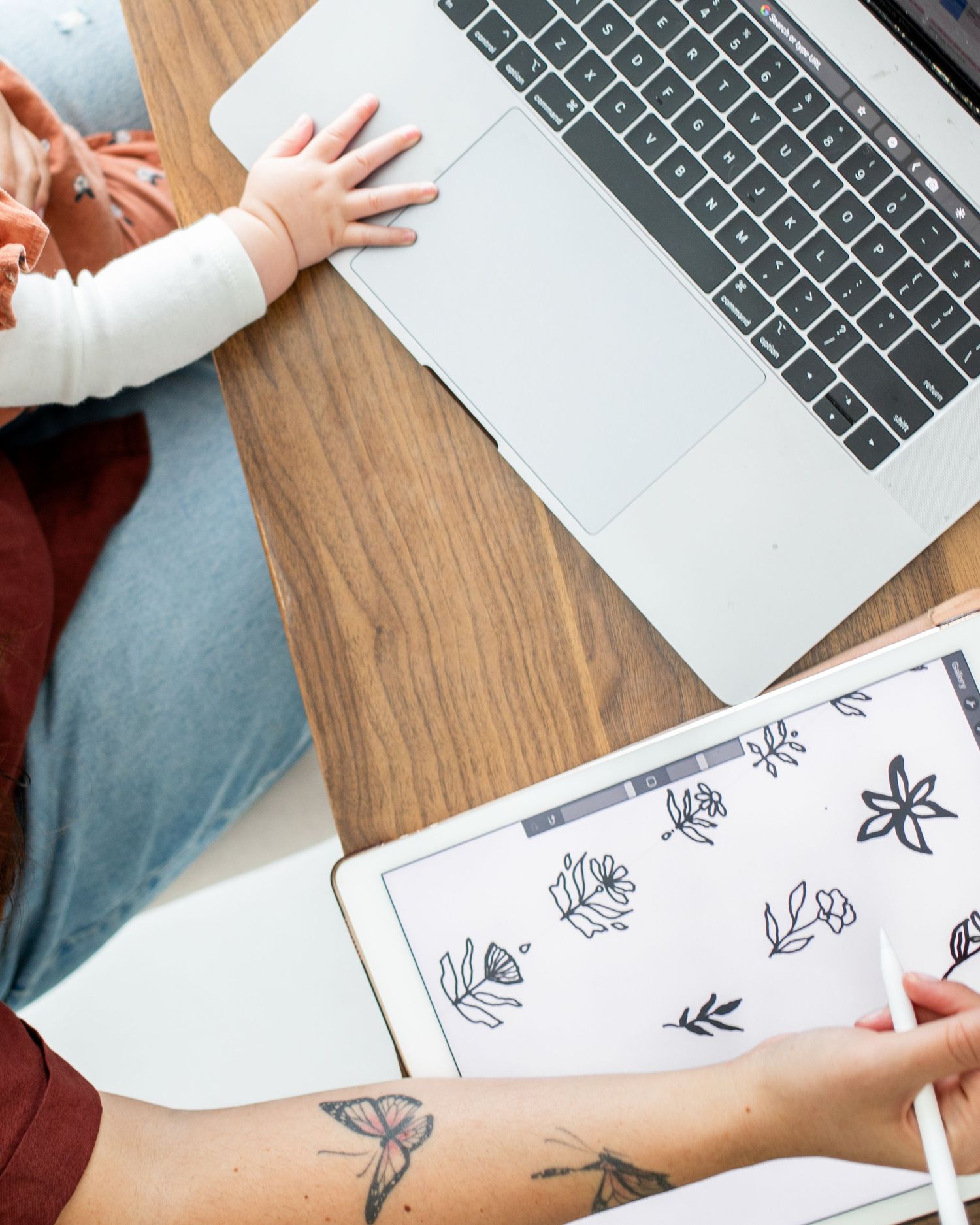 An image of a person's hands using a laptop computer and drawing on a tablet.