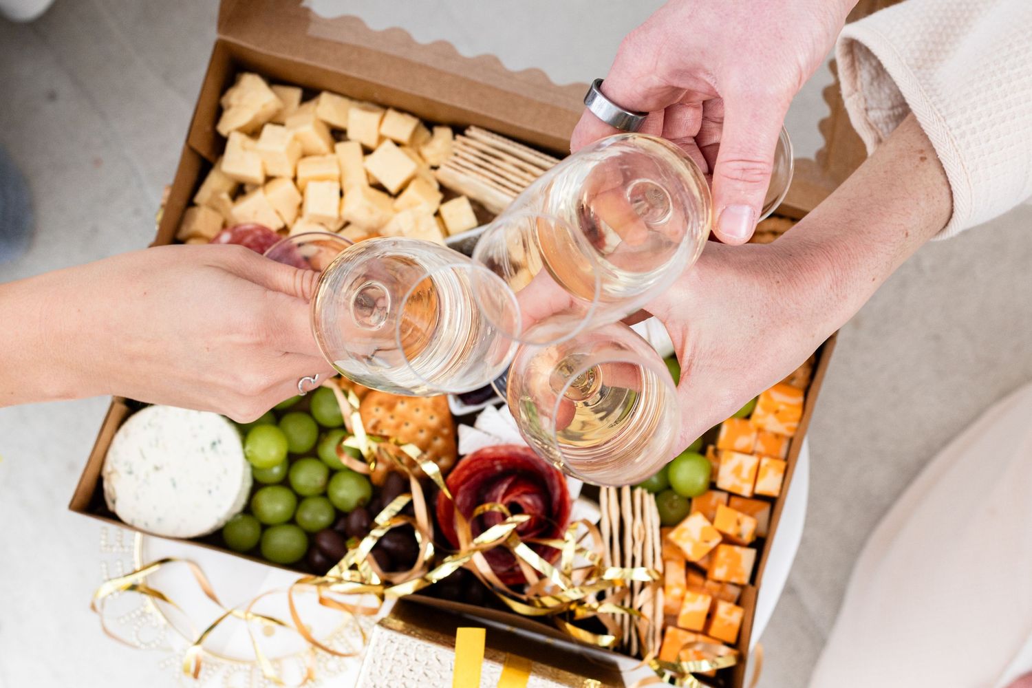 Hands reaching into a wooden crate filled with various snack items.
