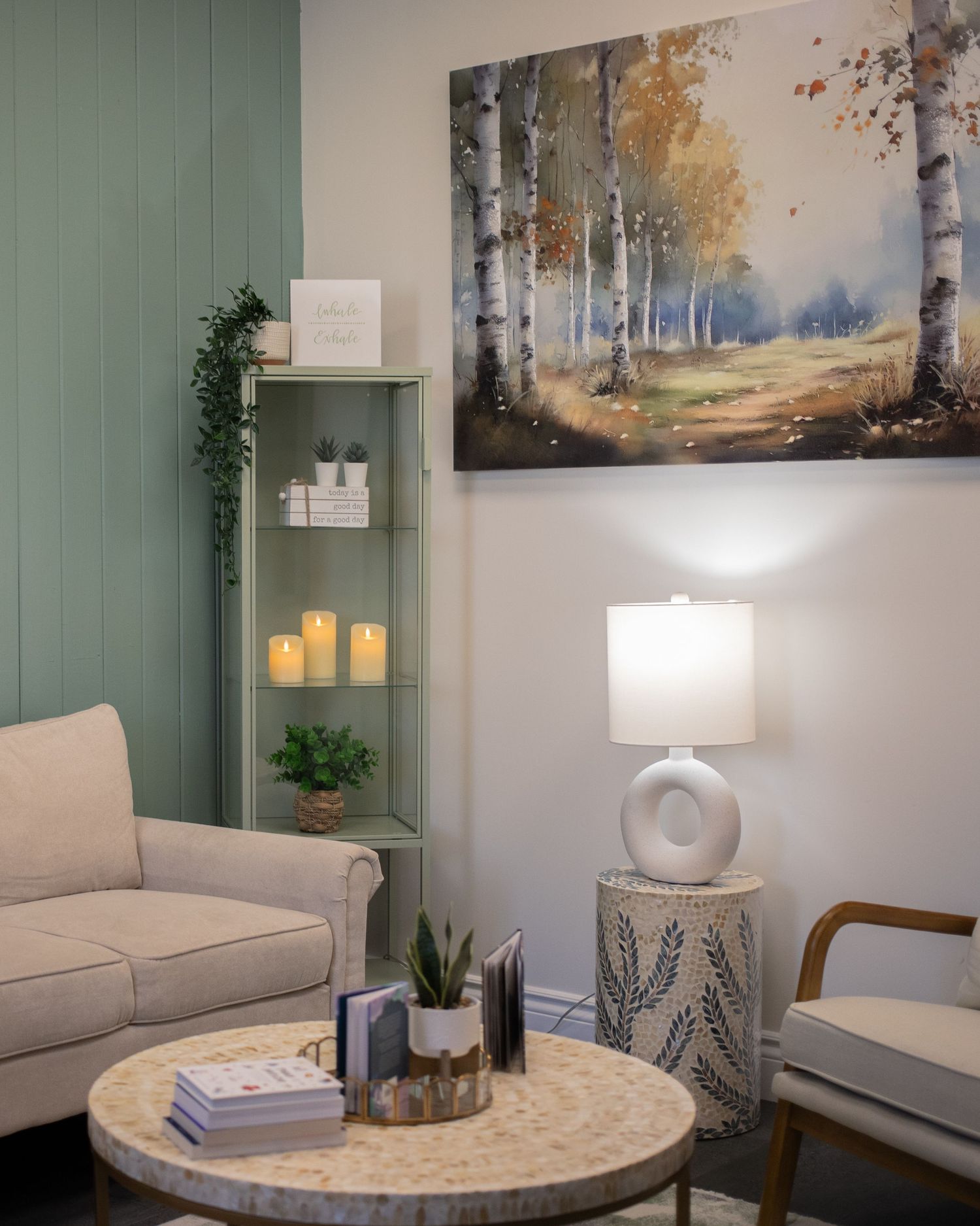 A cozy living room interior with a painting on the wall, a sofa, and a lamp.