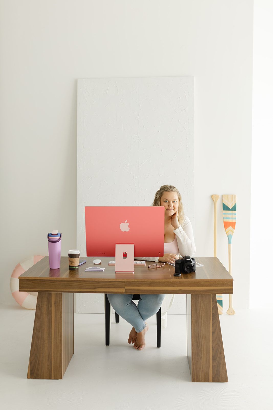 A woman sitting at a desk in a home office, using a computer and surrounded by various office supplies.