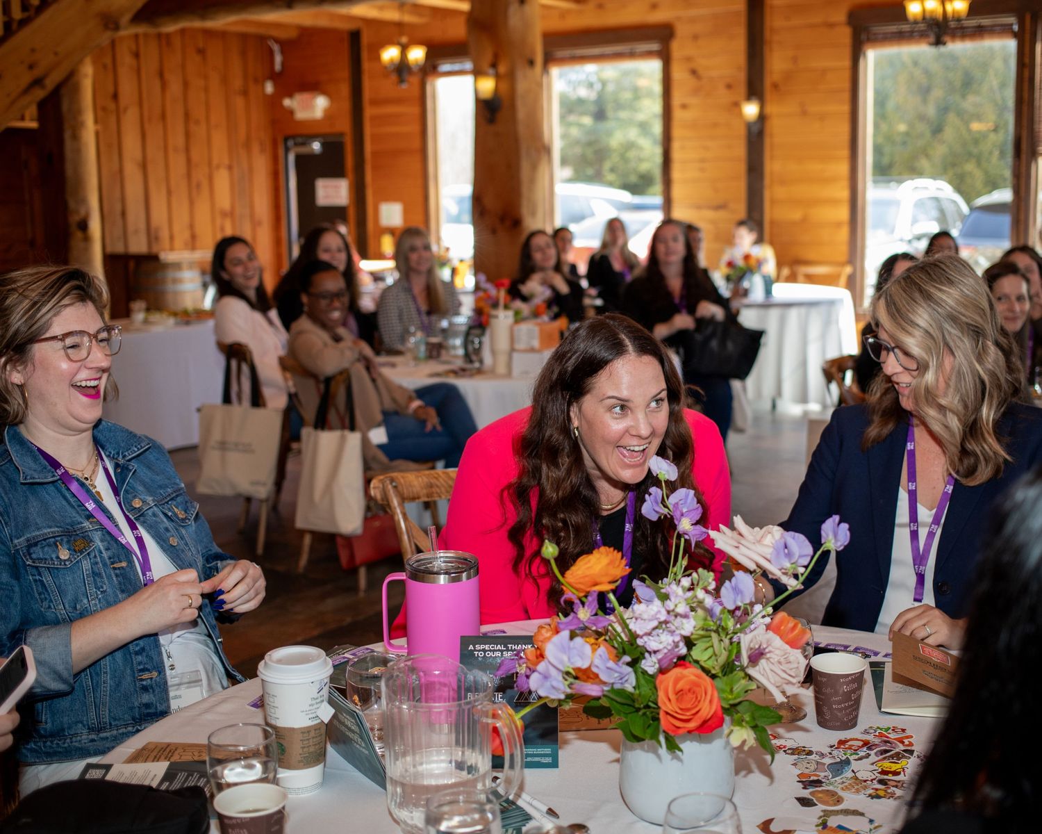 A group of people sitting at tables in a rustic indoor setting.