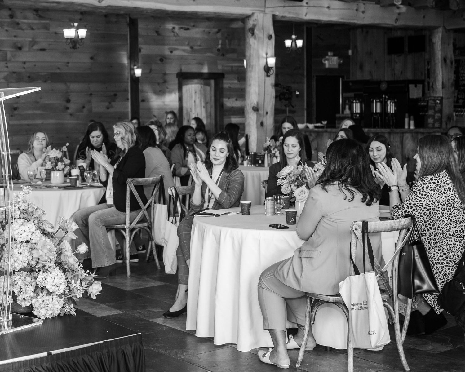 A group of people sitting at tables in a rustic indoor setting.